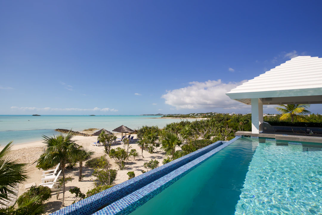 infinity pool overlooking a palm beach and turquoise sea