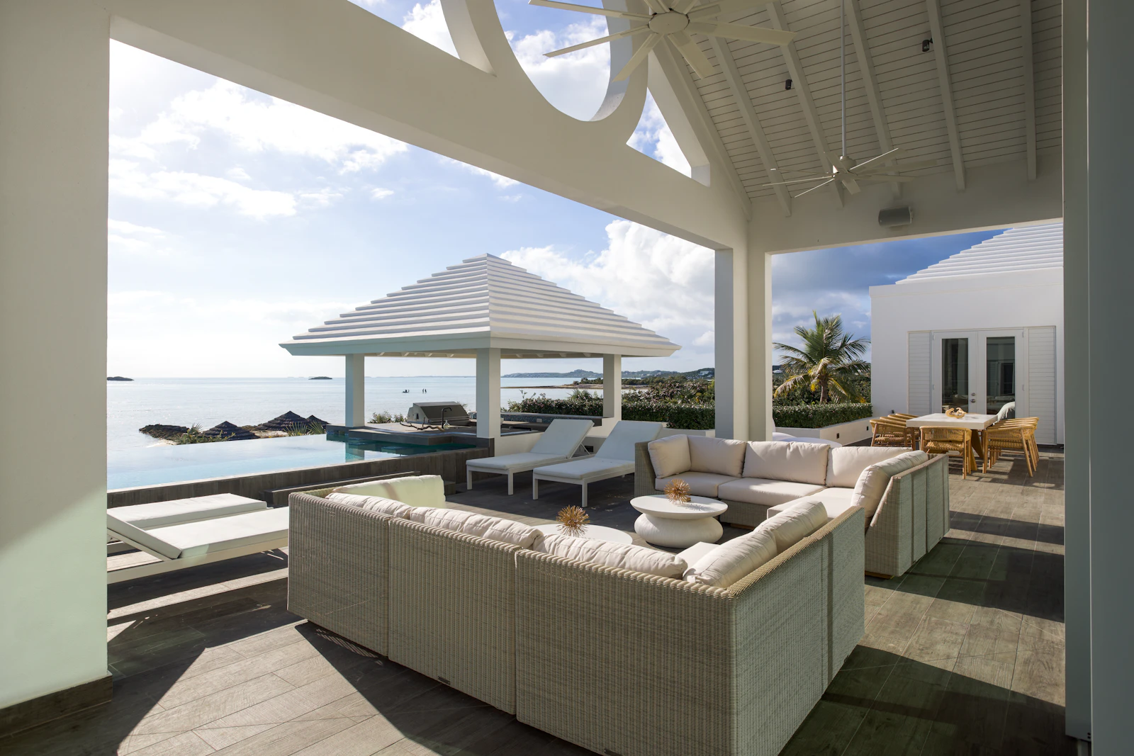 covered patio with white sofas over an infinity pool and the ocean