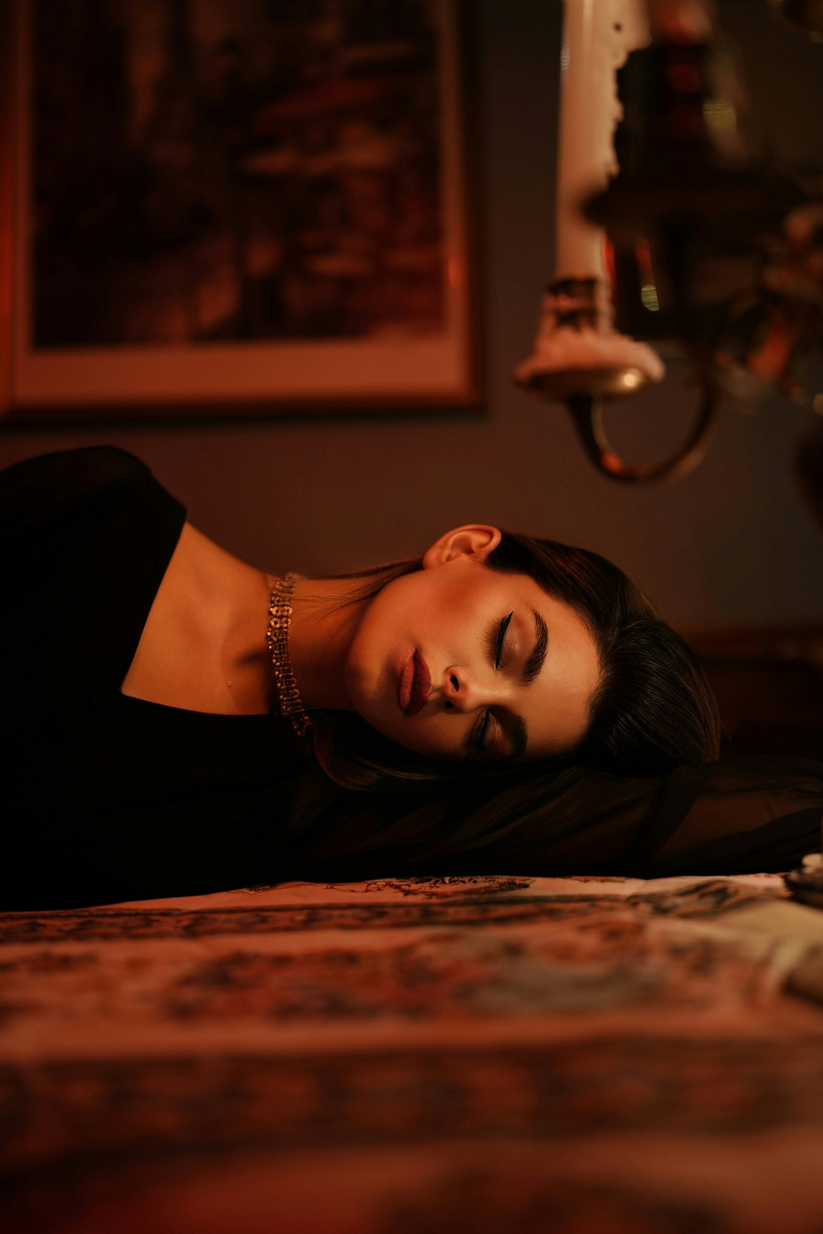 Una donna in abito nero sdraiata su un letto decorato in una luce calda