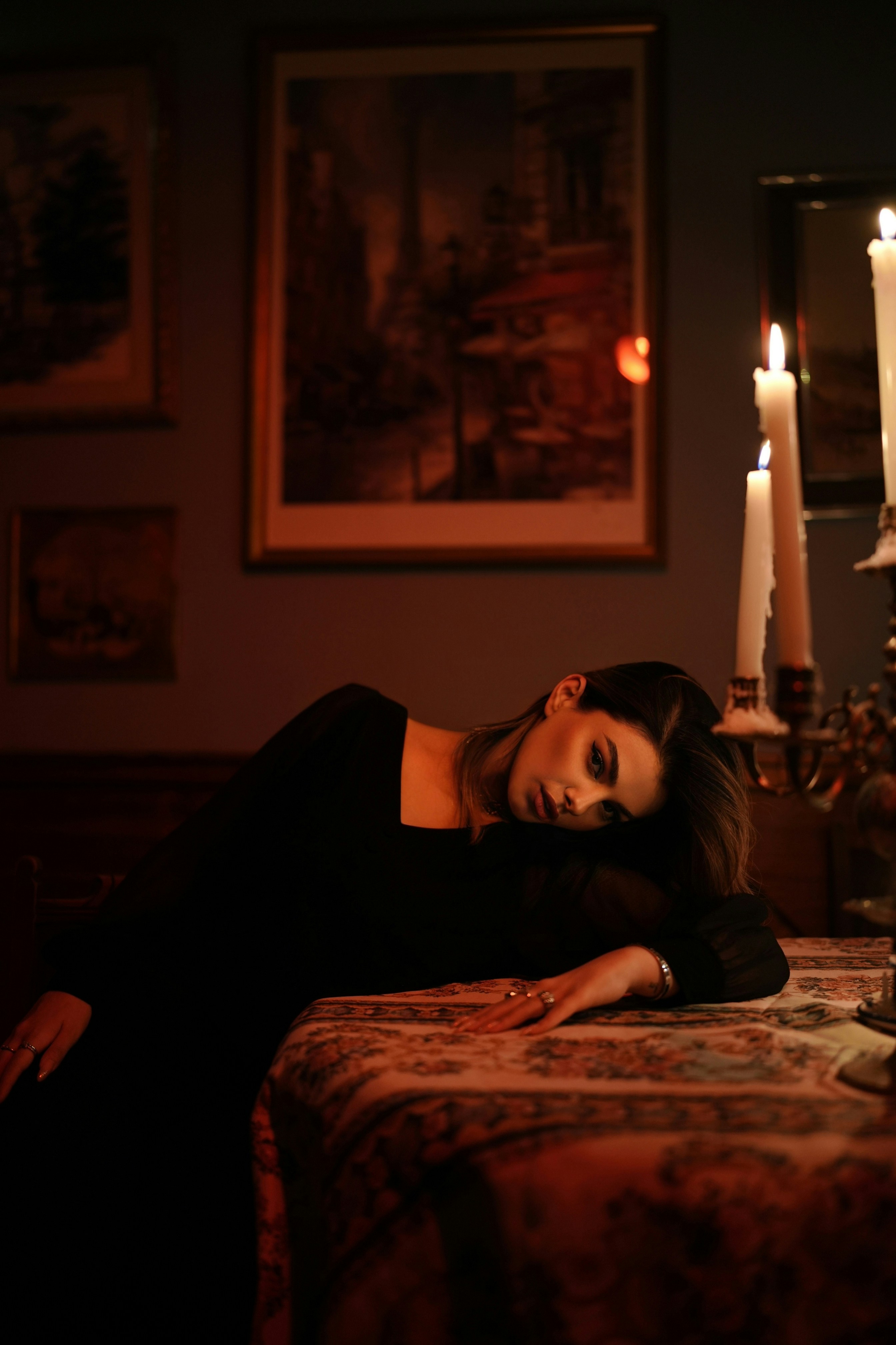 Una donna in abito nero appoggiata a una tovaglia decorata alla luce di una candela