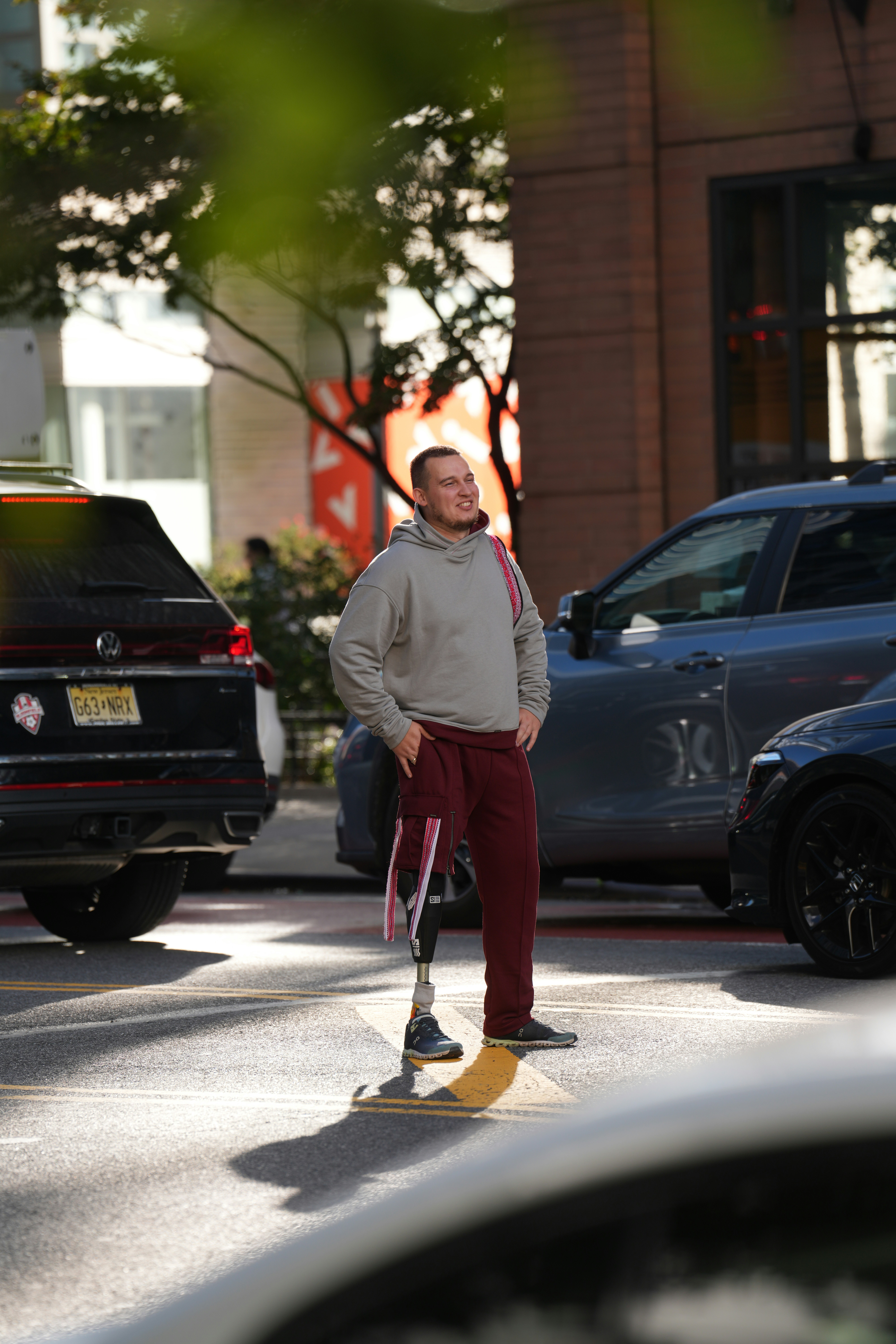 A man with a prosthetic leg wearing a grey hoodie and maroon sweatpants