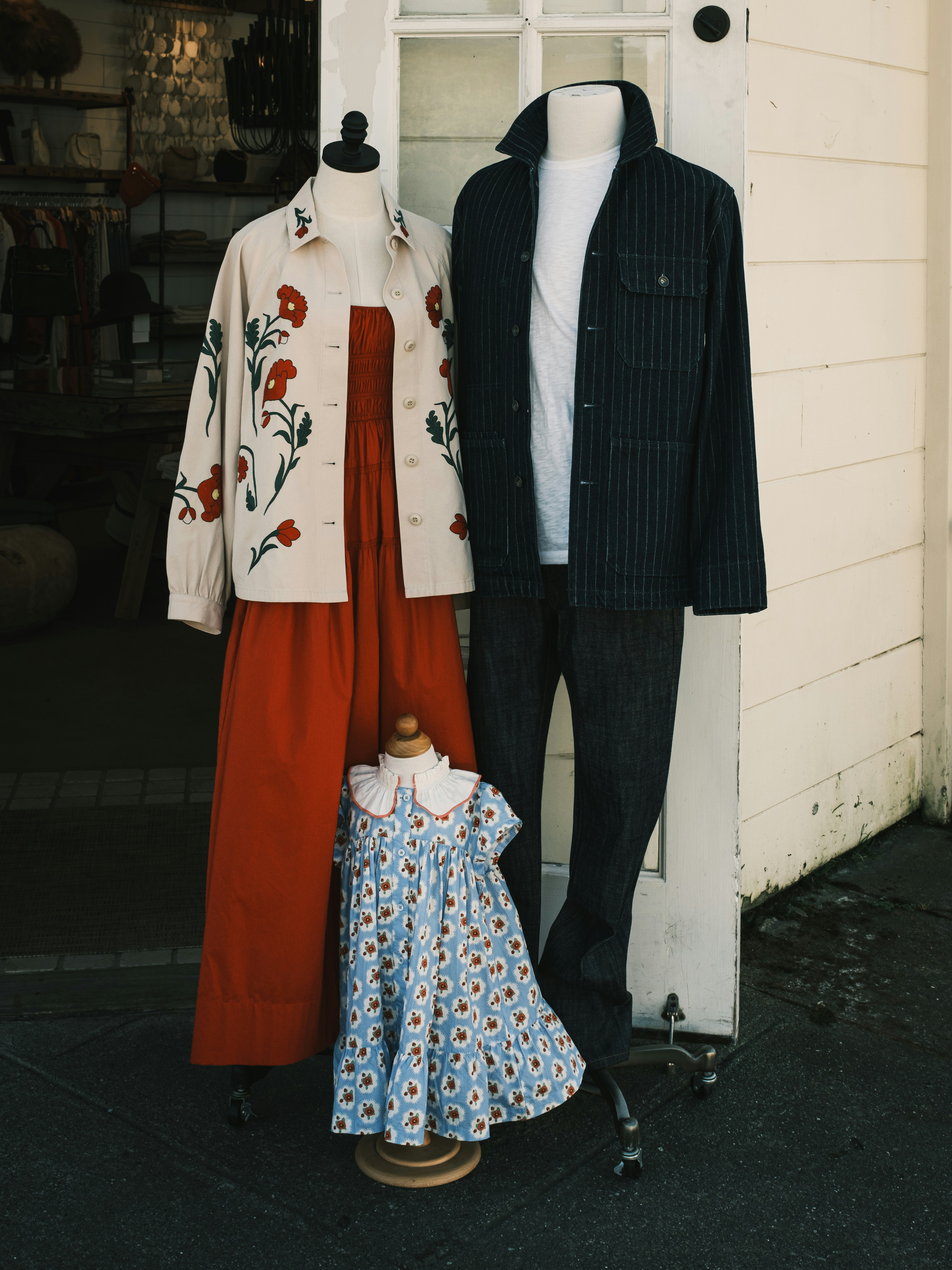 Three mannequins wearing floral and striped clothing outside a shop entrance