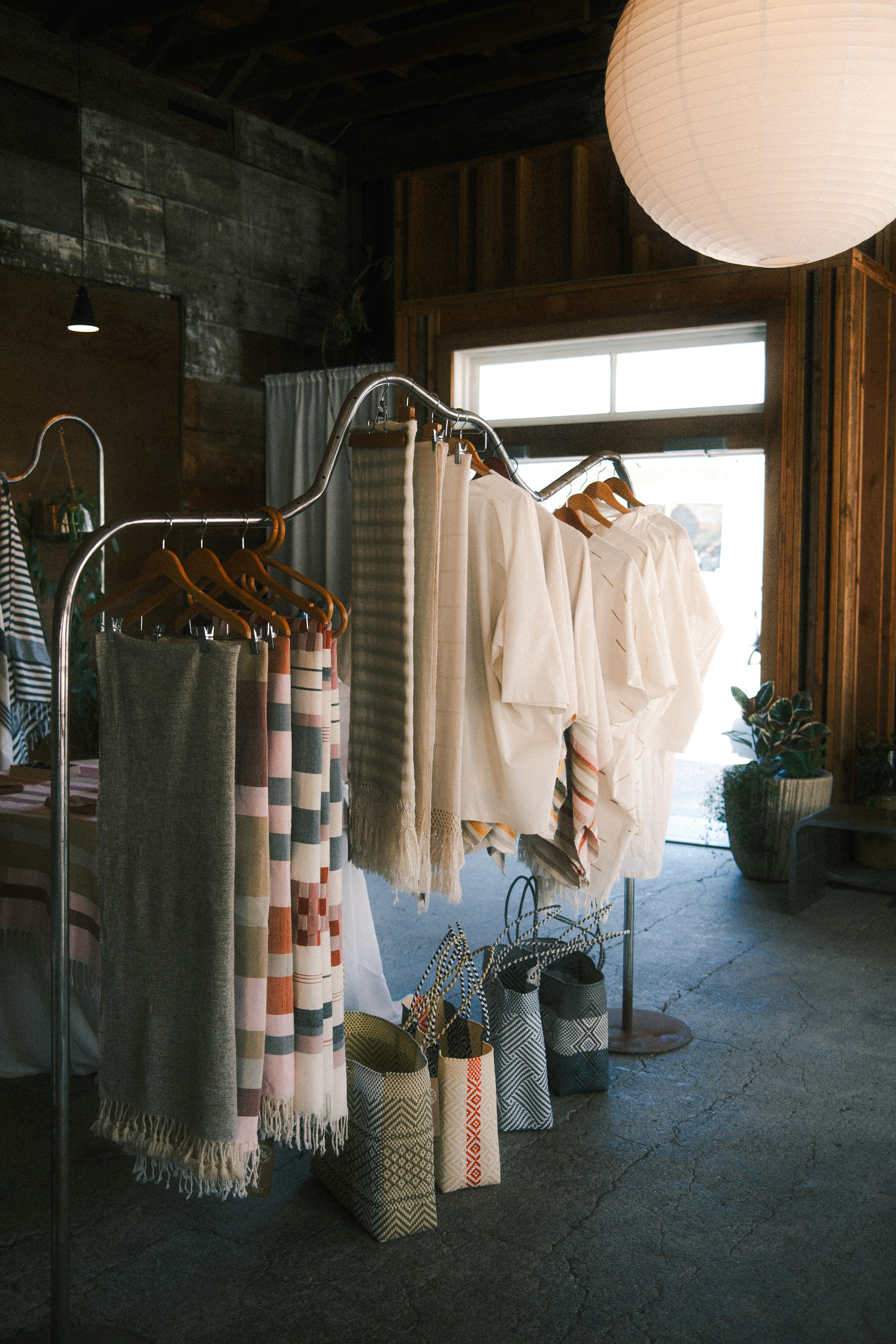 Textiles and clothing on a metal rack in a sunlit boutique shop