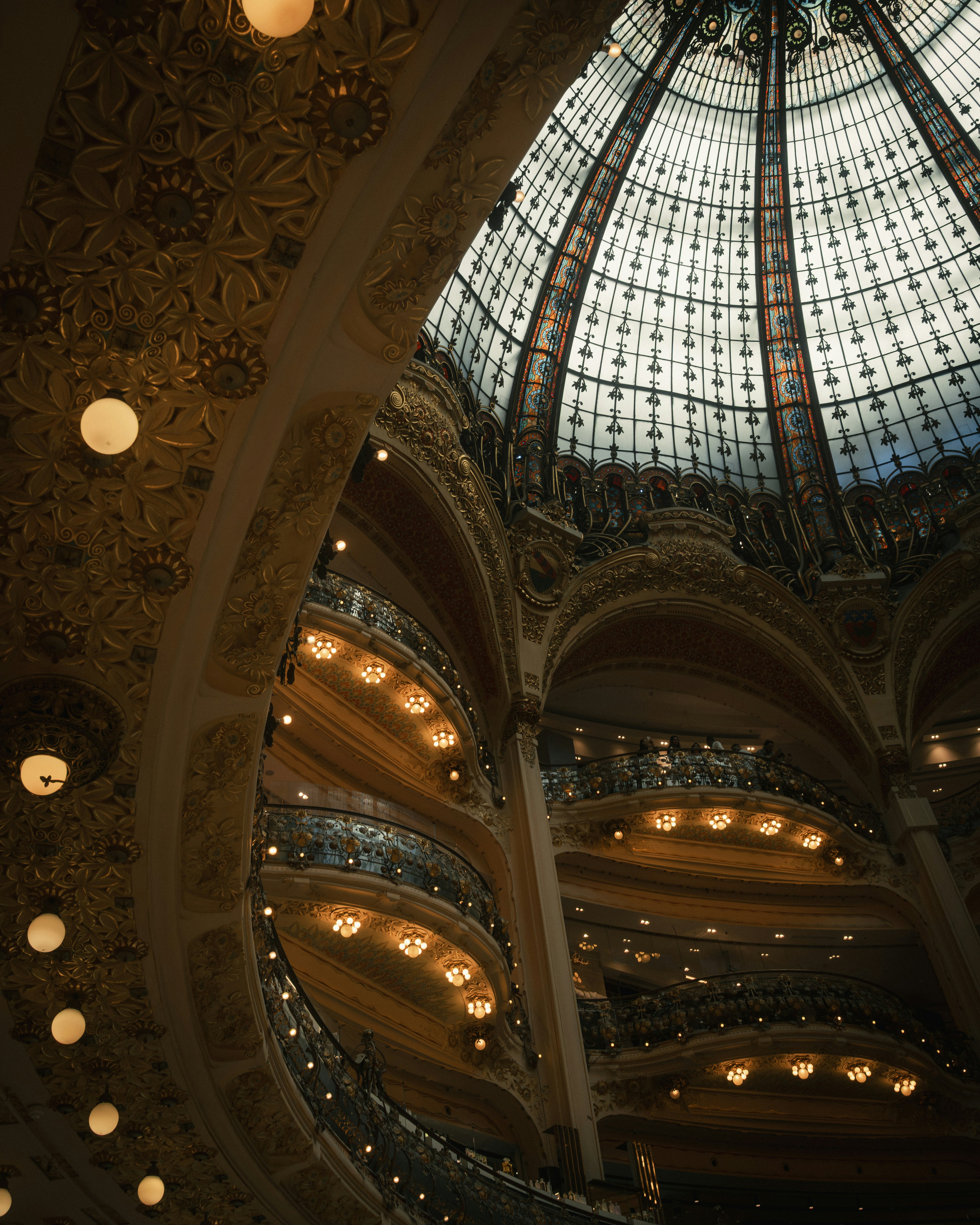 The ornate stained glass dome and tiered balconies of Galeries Lafayette in Paris