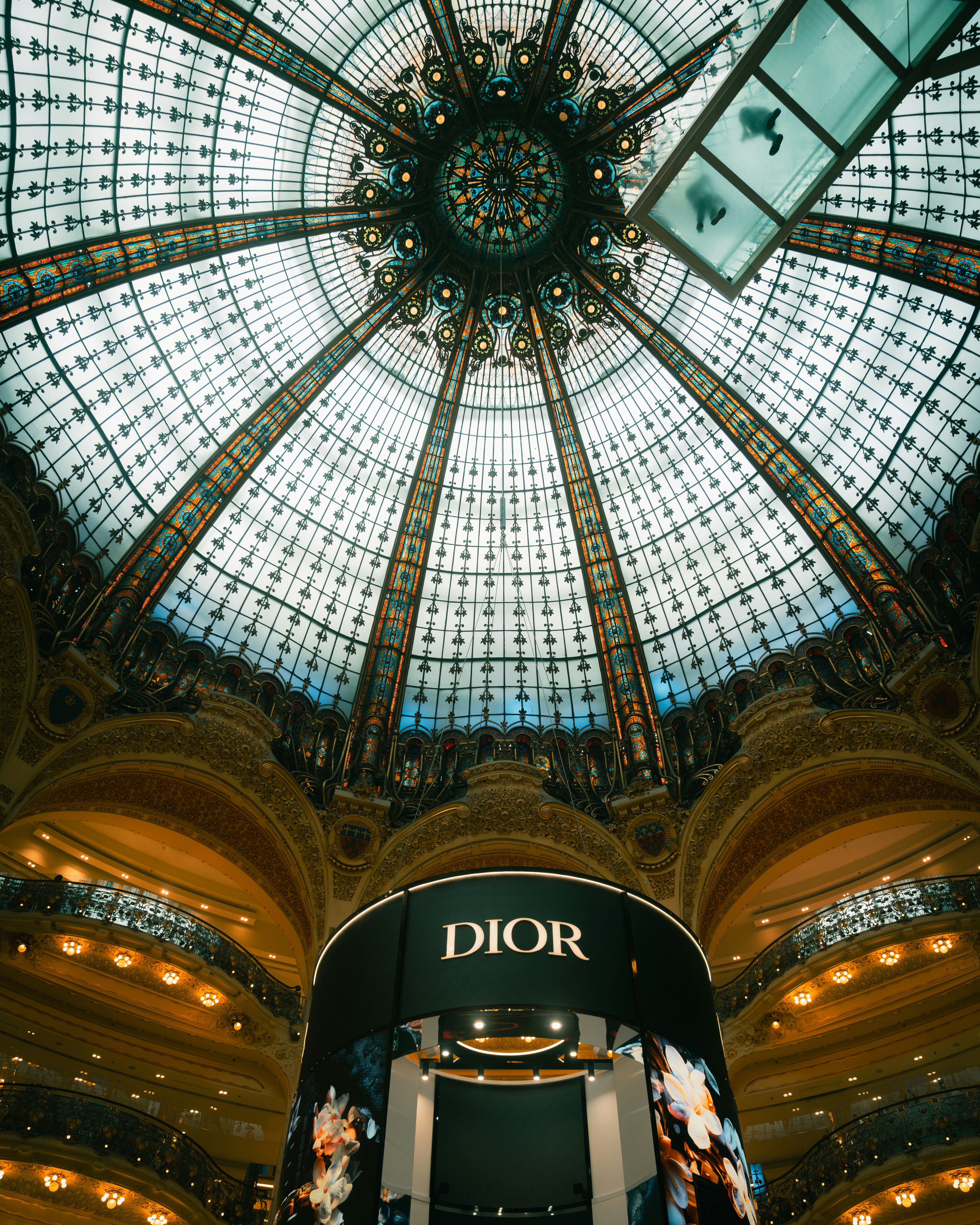 The ornate stained glass dome of Galeries Lafayette in Paris with a Dior display