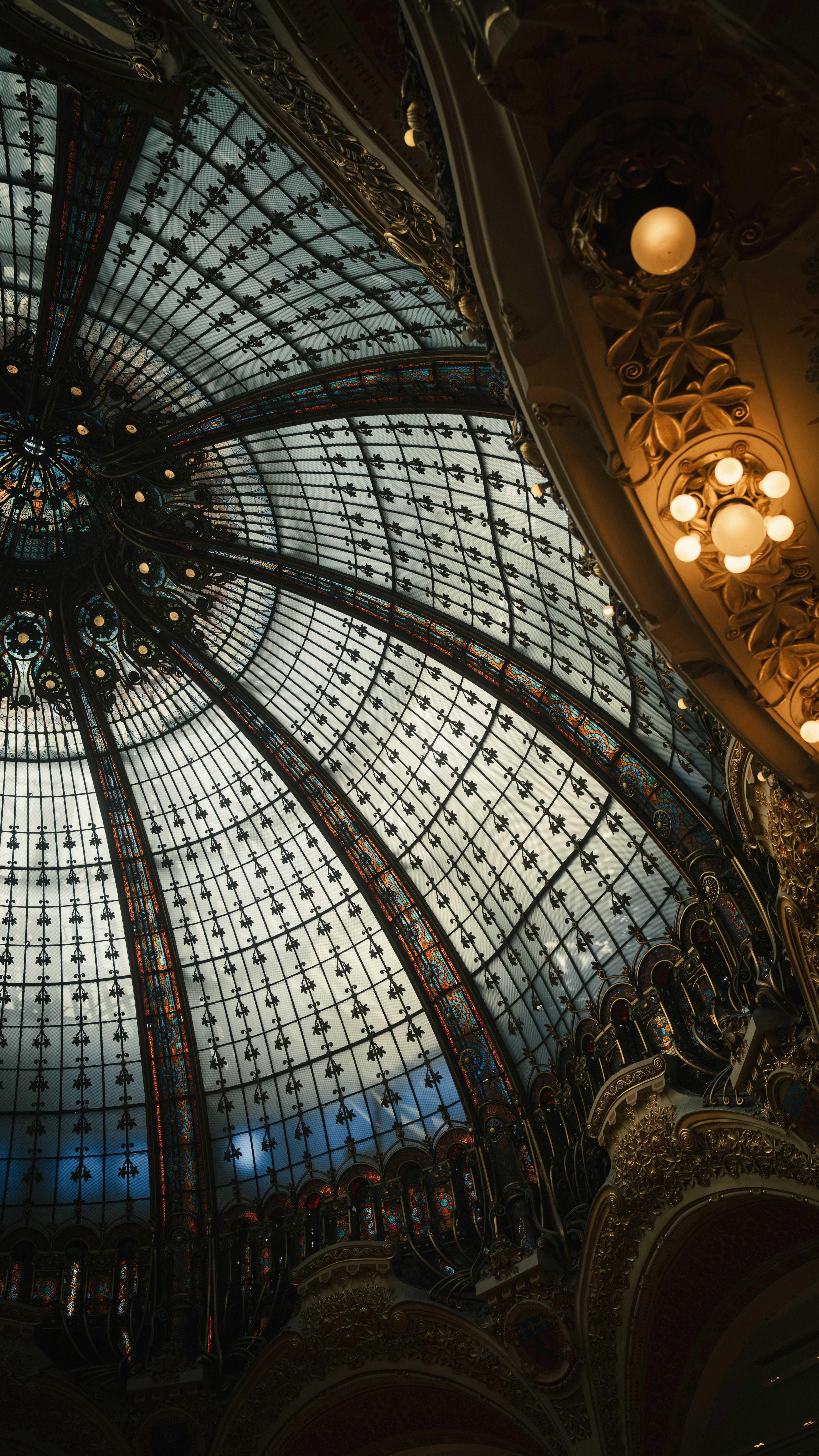The ornate stained glass dome of Galeries Lafayette in Paris with golden light