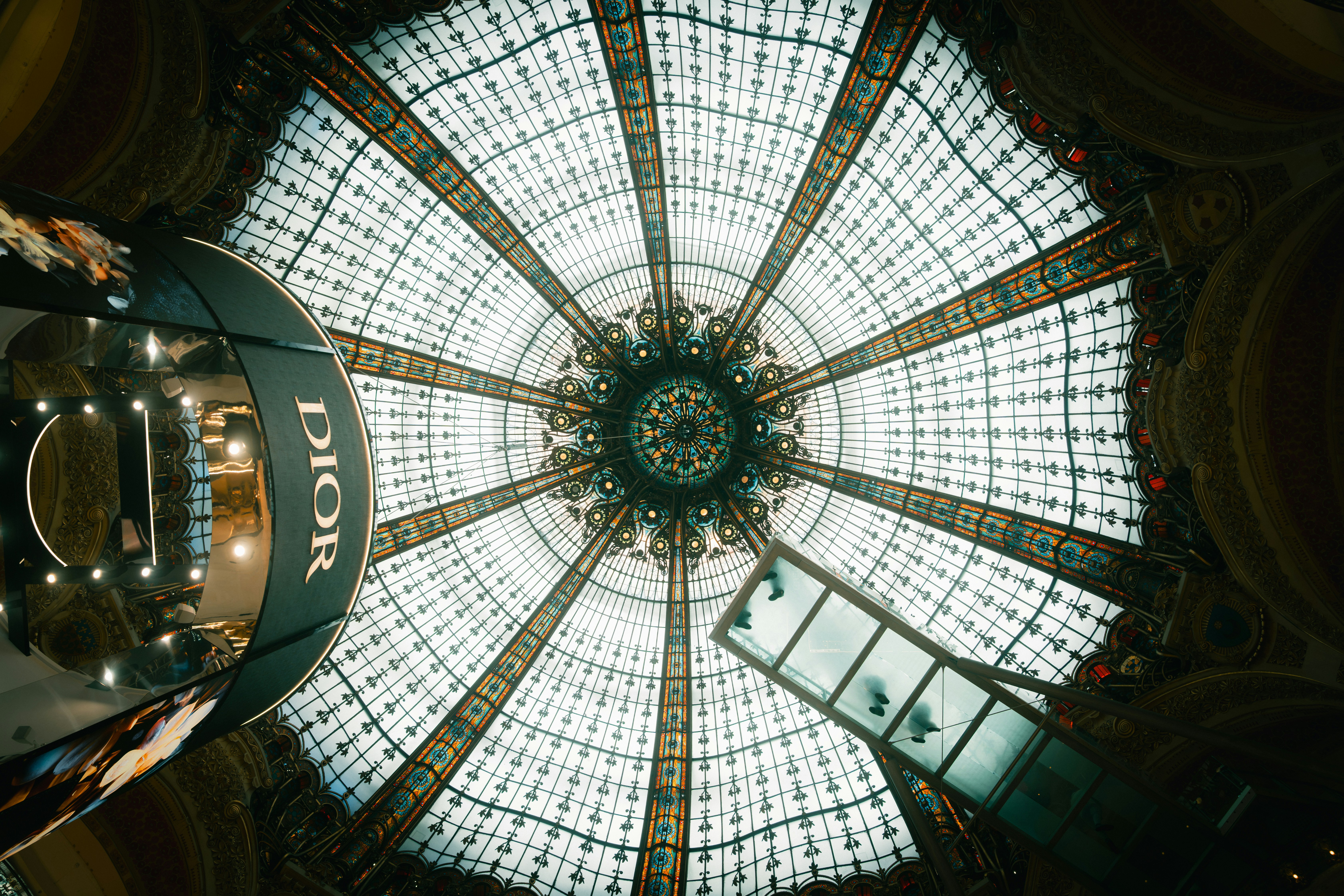 The ornate stained glass dome of Galeries Lafayette in Paris with a Dior display