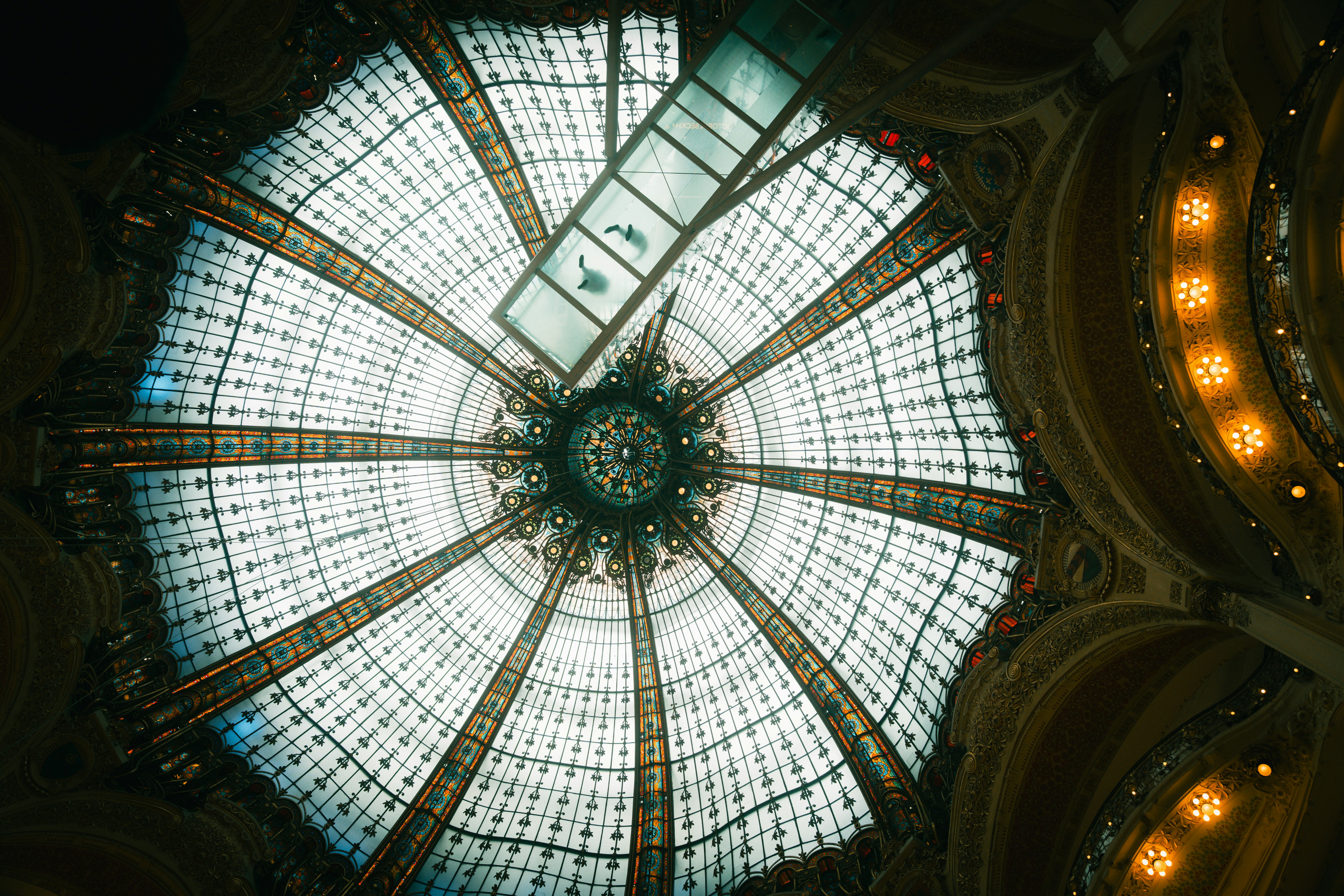 The ornate stained glass dome of Galeries Lafayette in Paris with a glass walkway