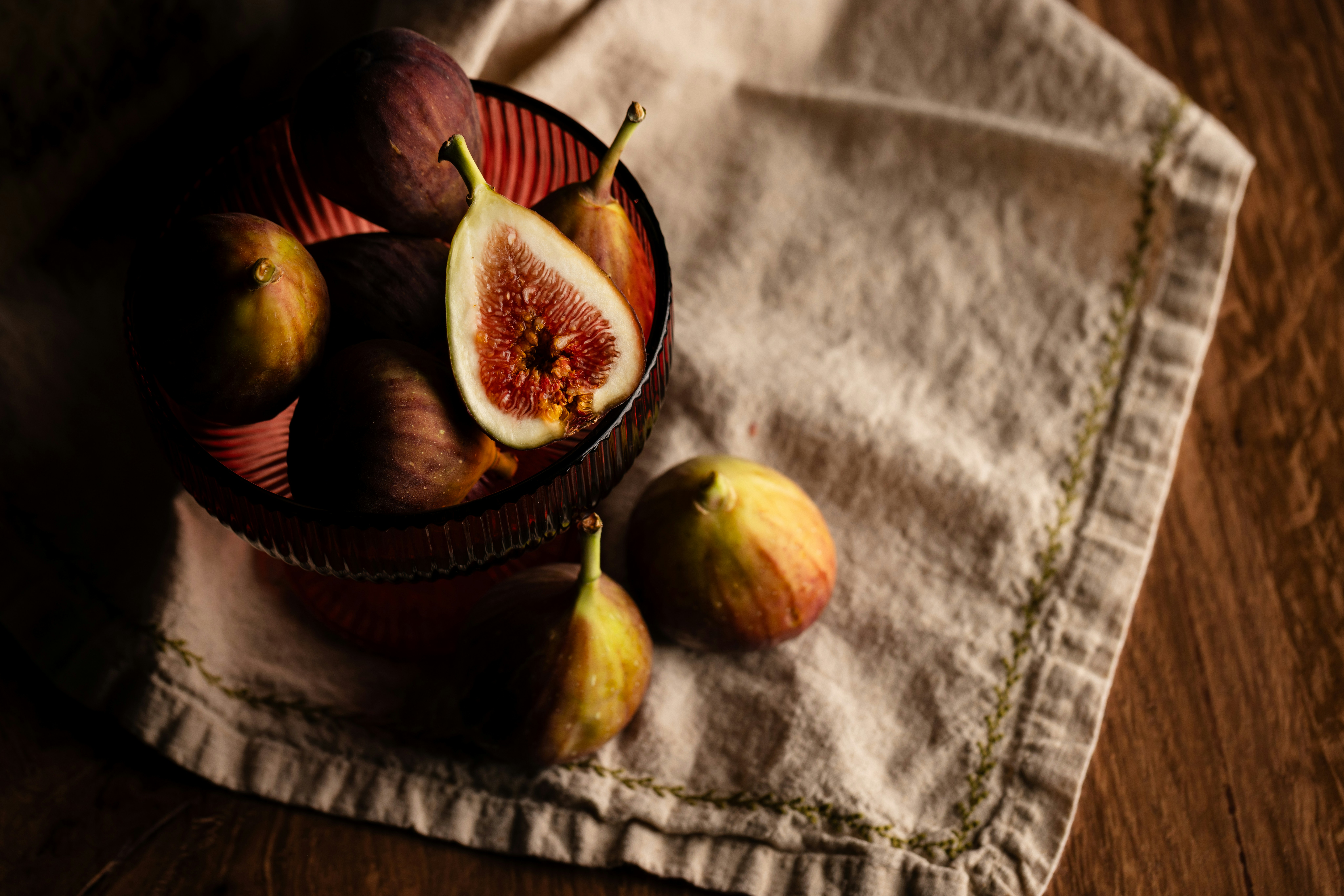 Fresh figs in a ribbed glass bowl on a linen cloth