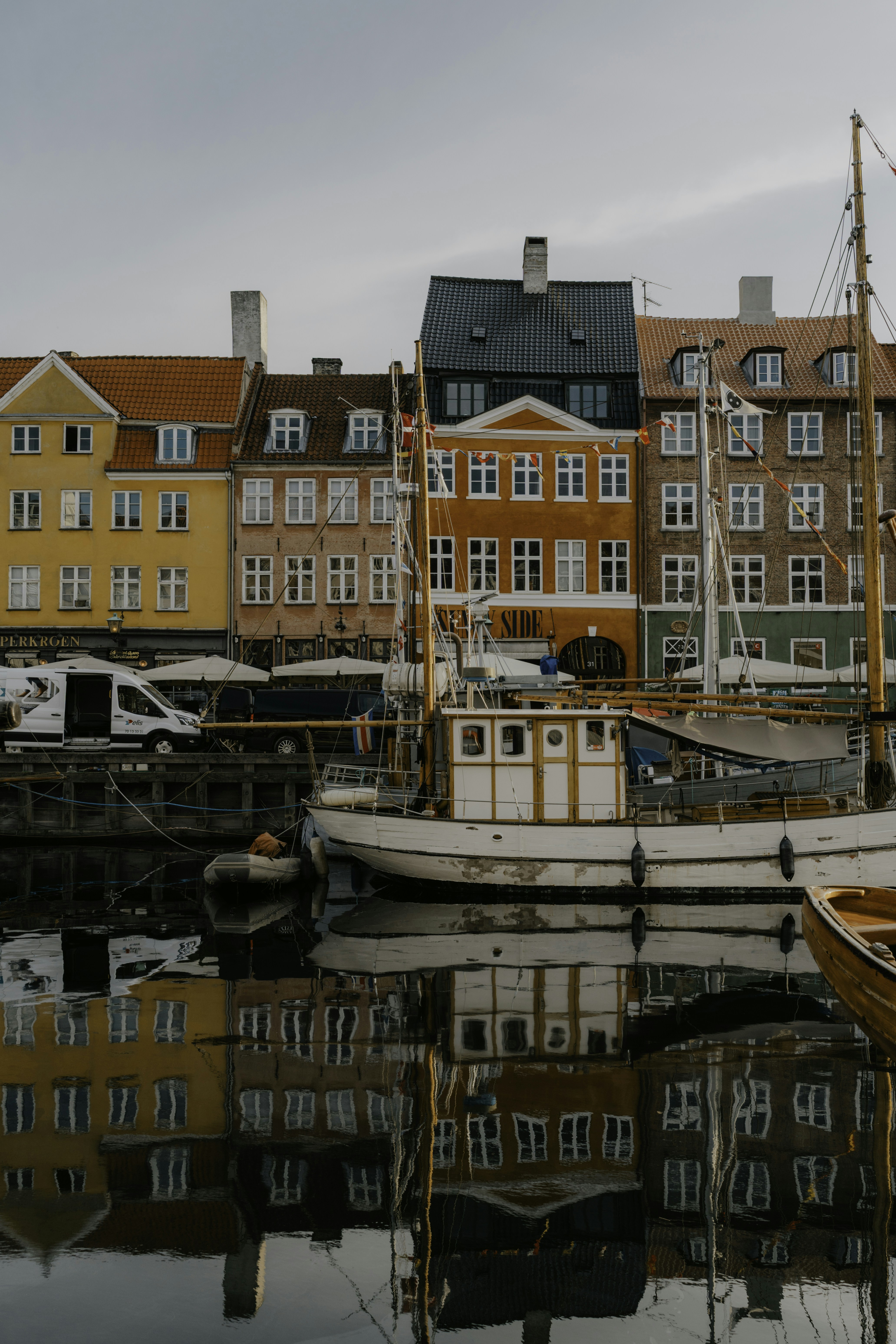 A white boat moored in Nyhavn canal before colorful historic buildings in Copenhagen