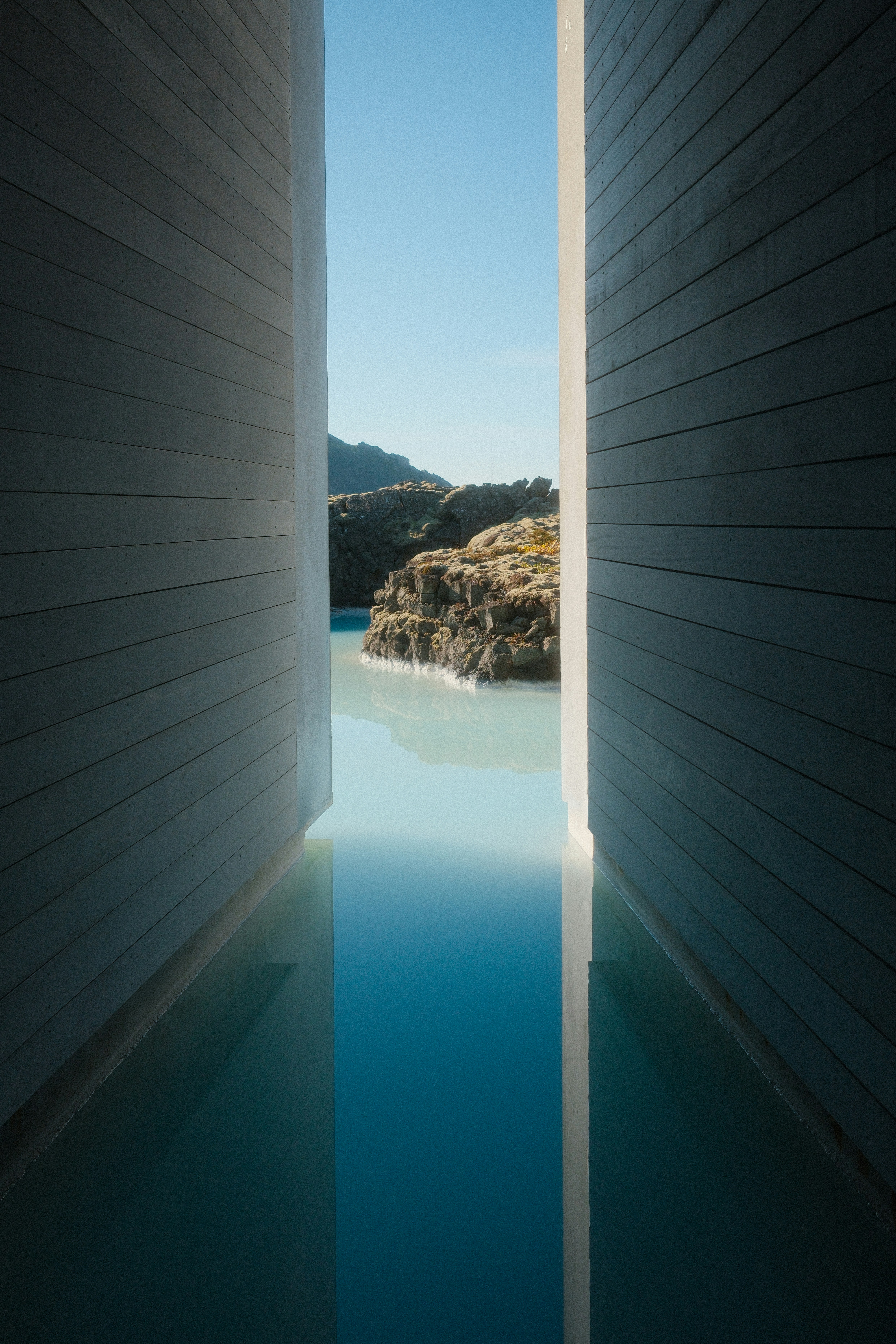 Milky blue water between two concrete walls leading to a rocky landscape