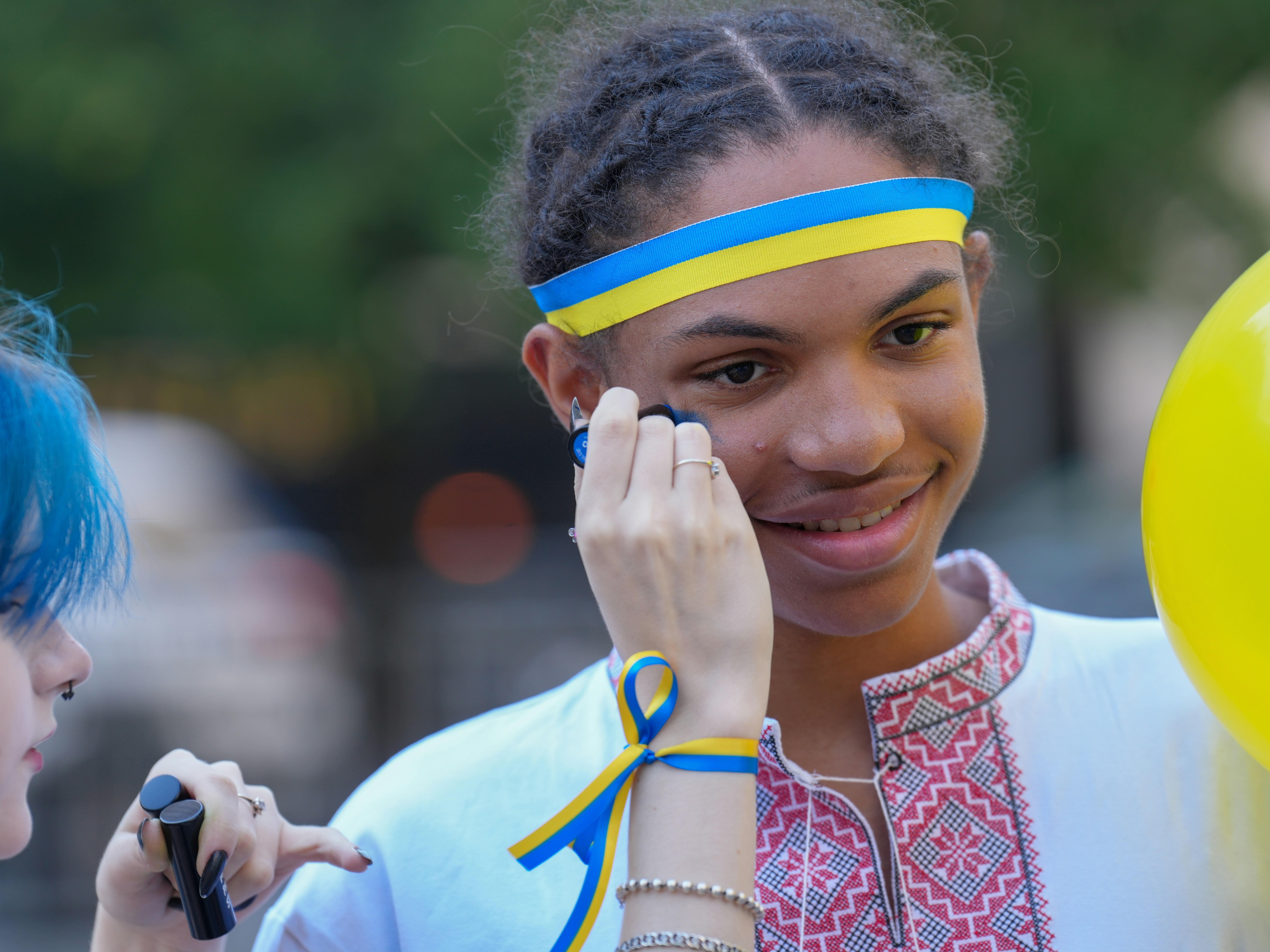 A person with a blue and yellow headband having face paint applied