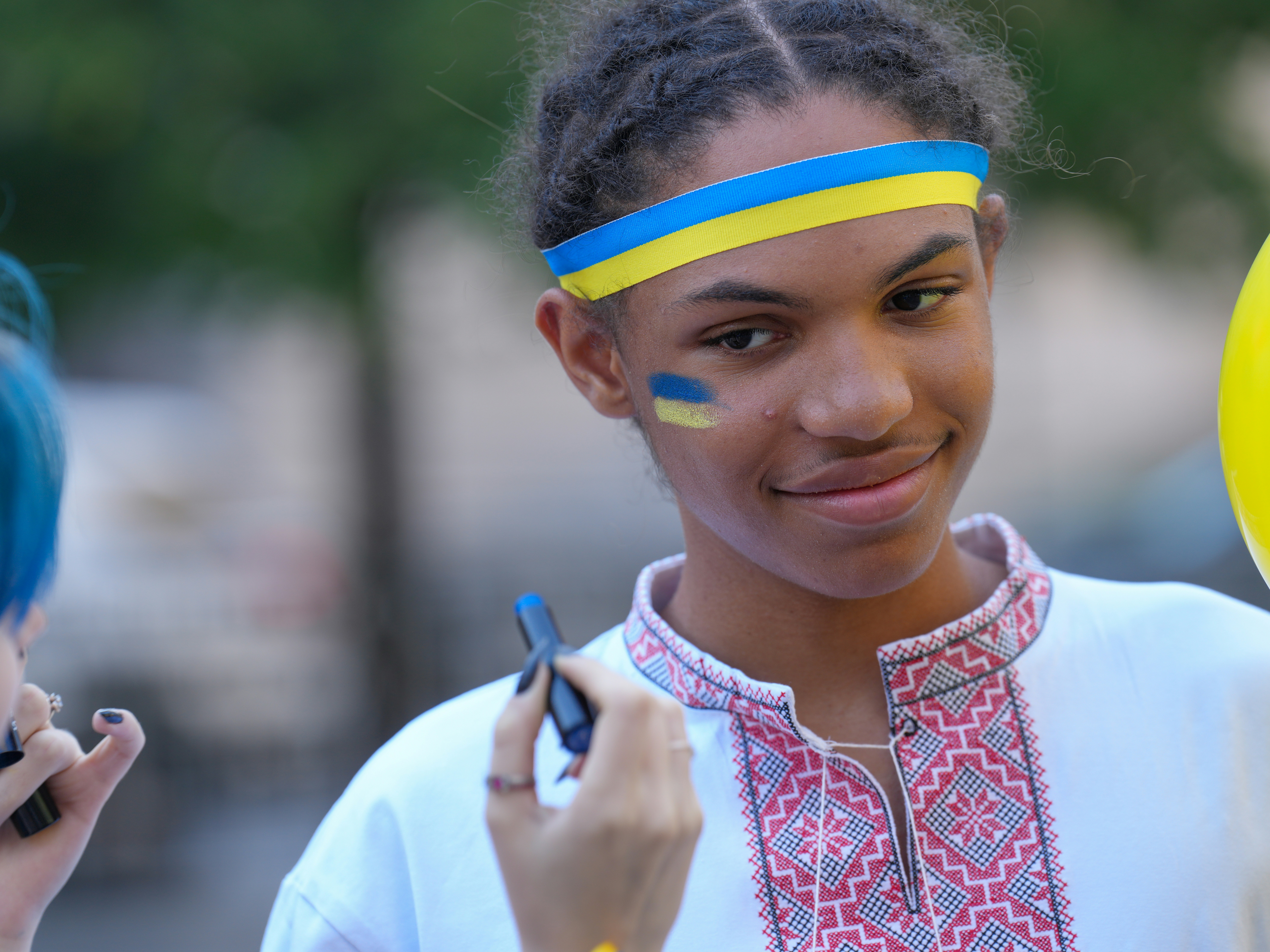A person wearing a Ukrainian flag headband and face paint in a traditional shirt