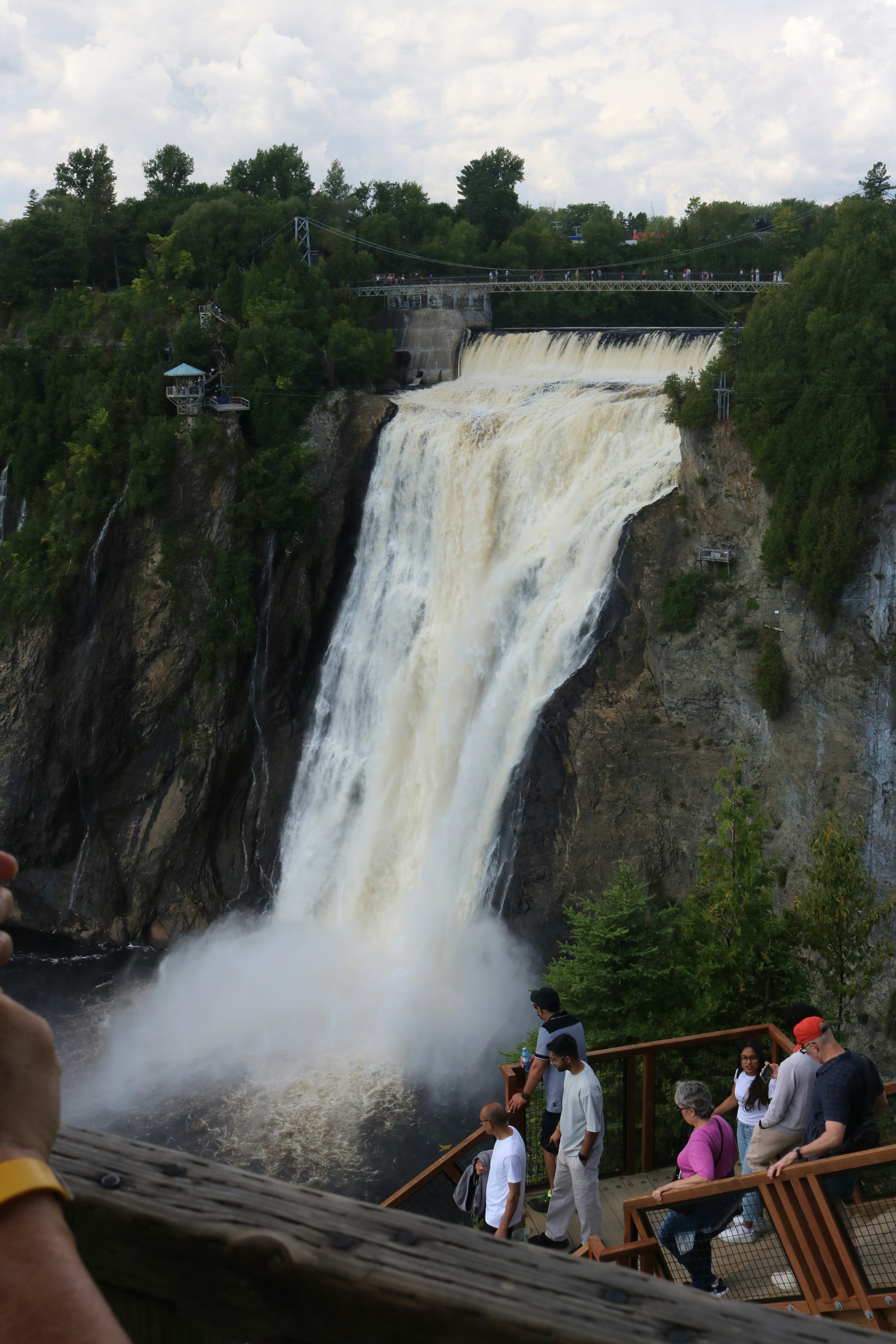 People on a wooden observation deck overlooking the large Montmorency Falls in Quebec