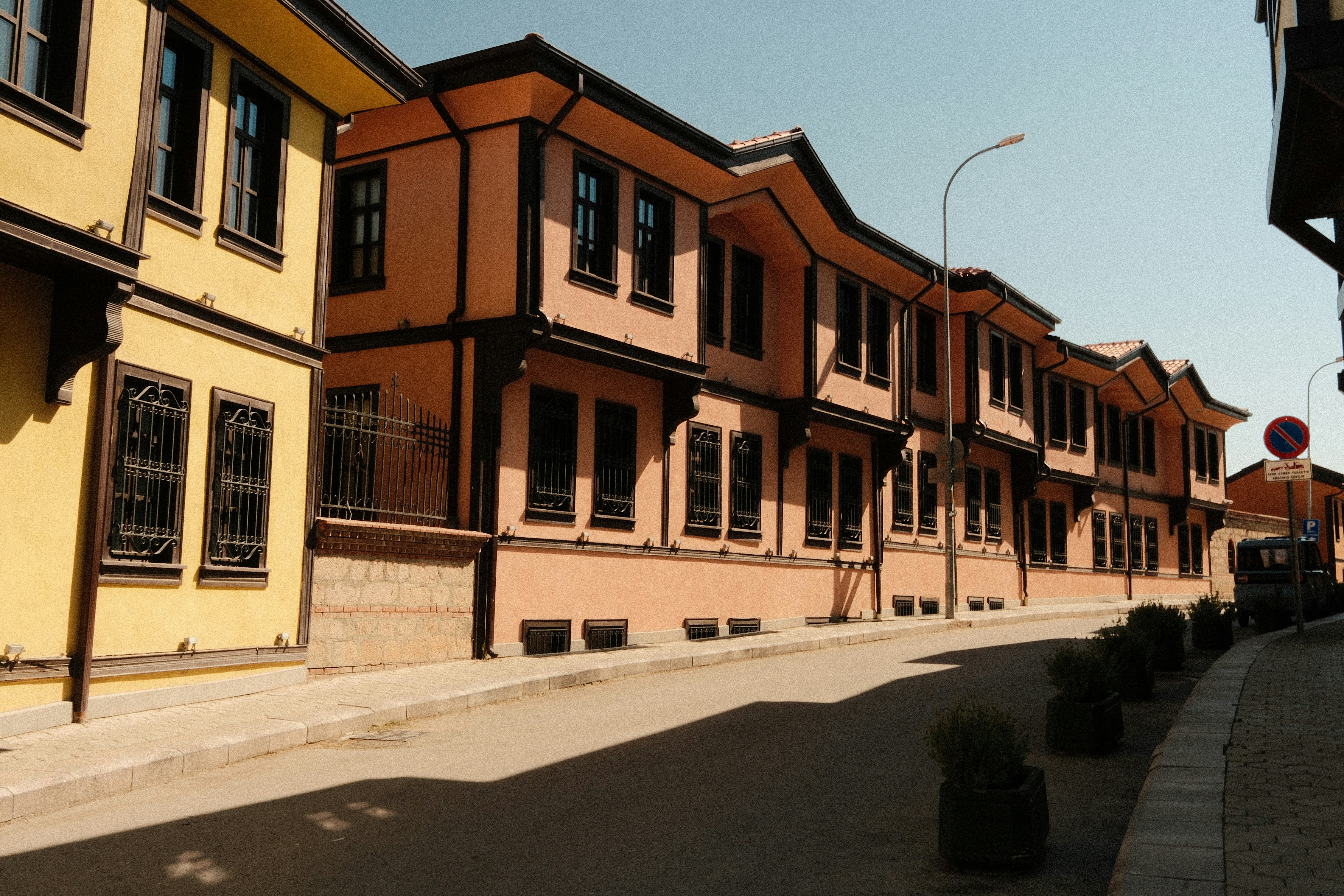 Yellow and peach colored houses with dark wooden trim along a quiet street
