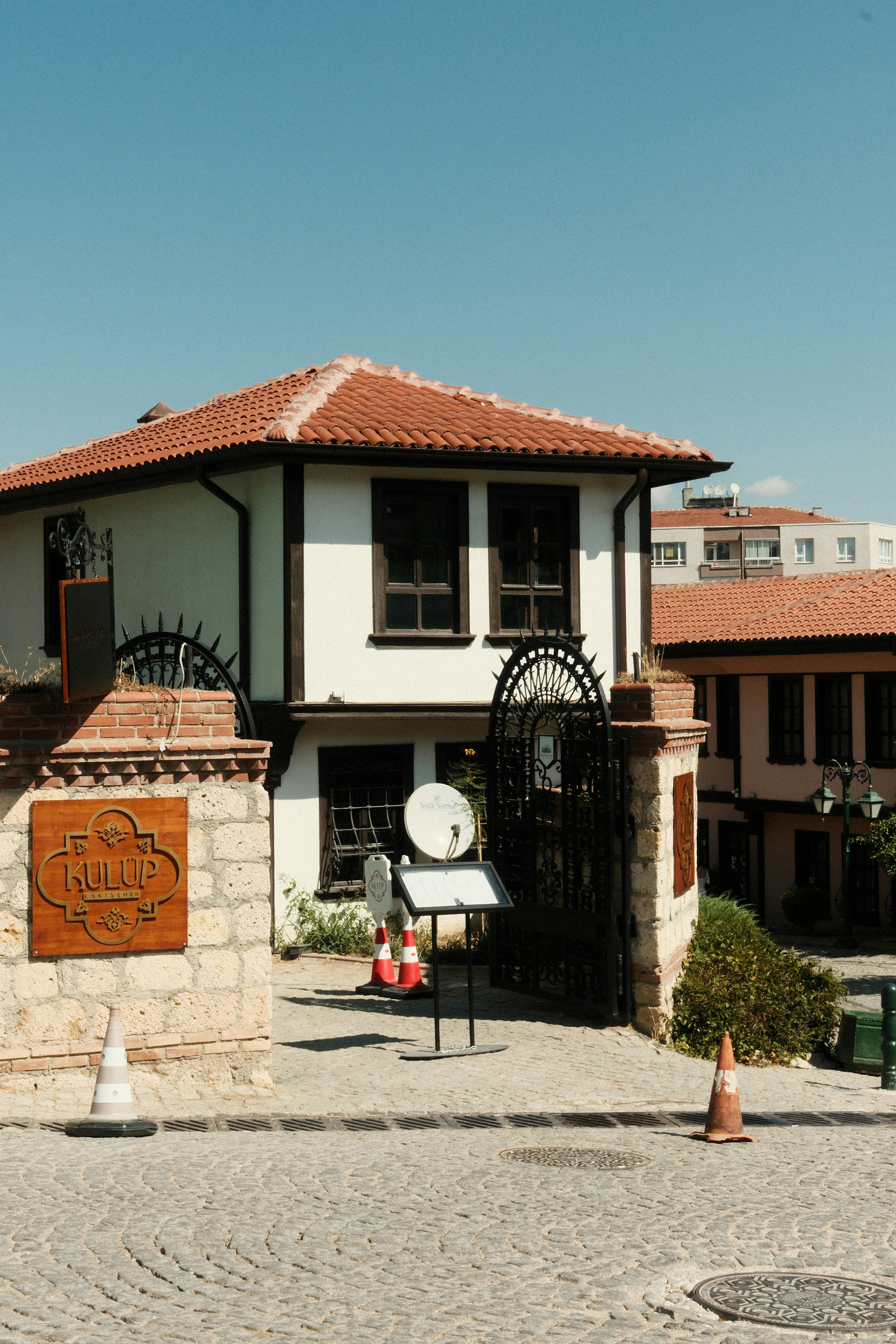 A white house with a terracotta roof behind a stone wall in Eskisehir