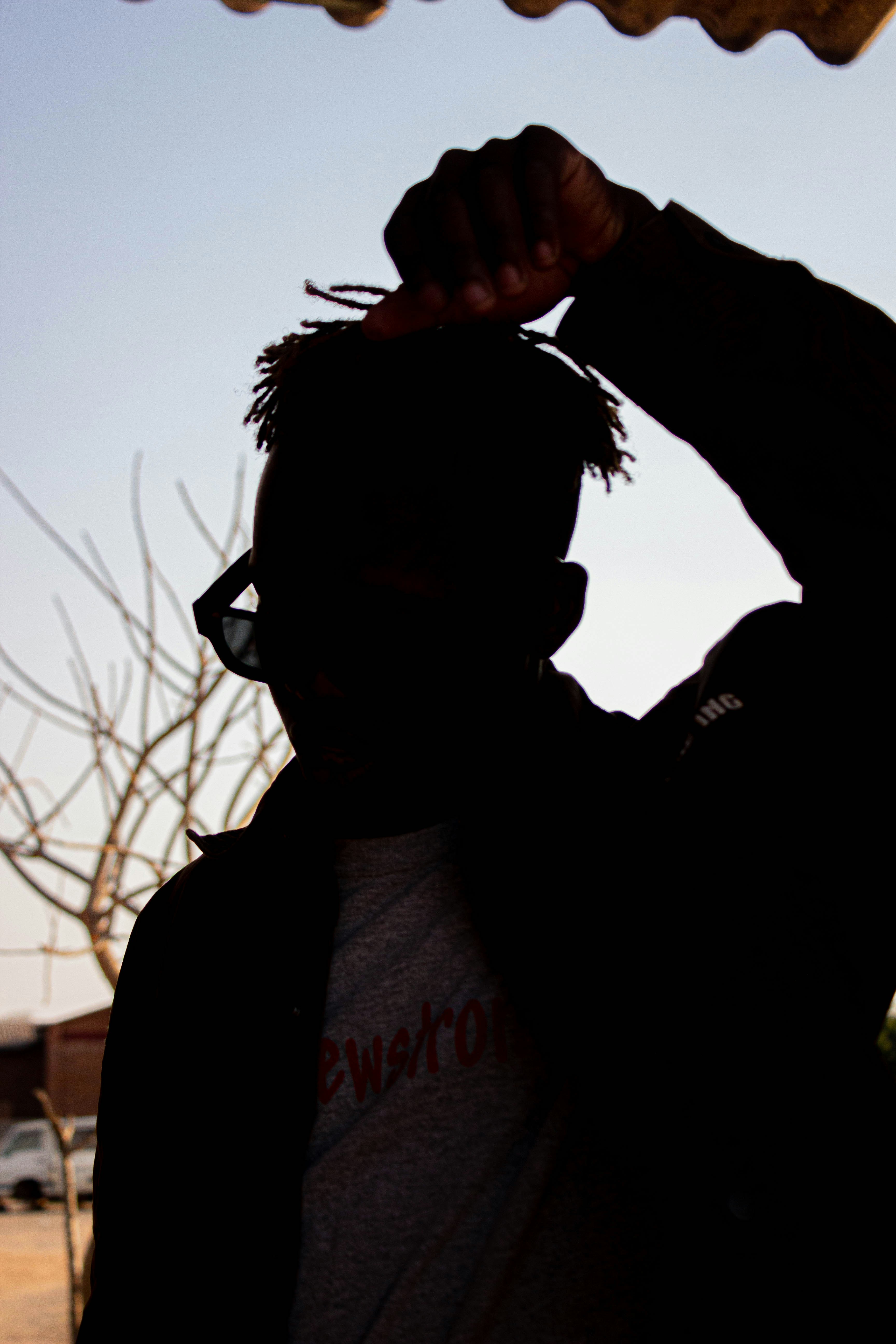 A person in silhouette wearing sunglasses and a jacket against a bright sky
