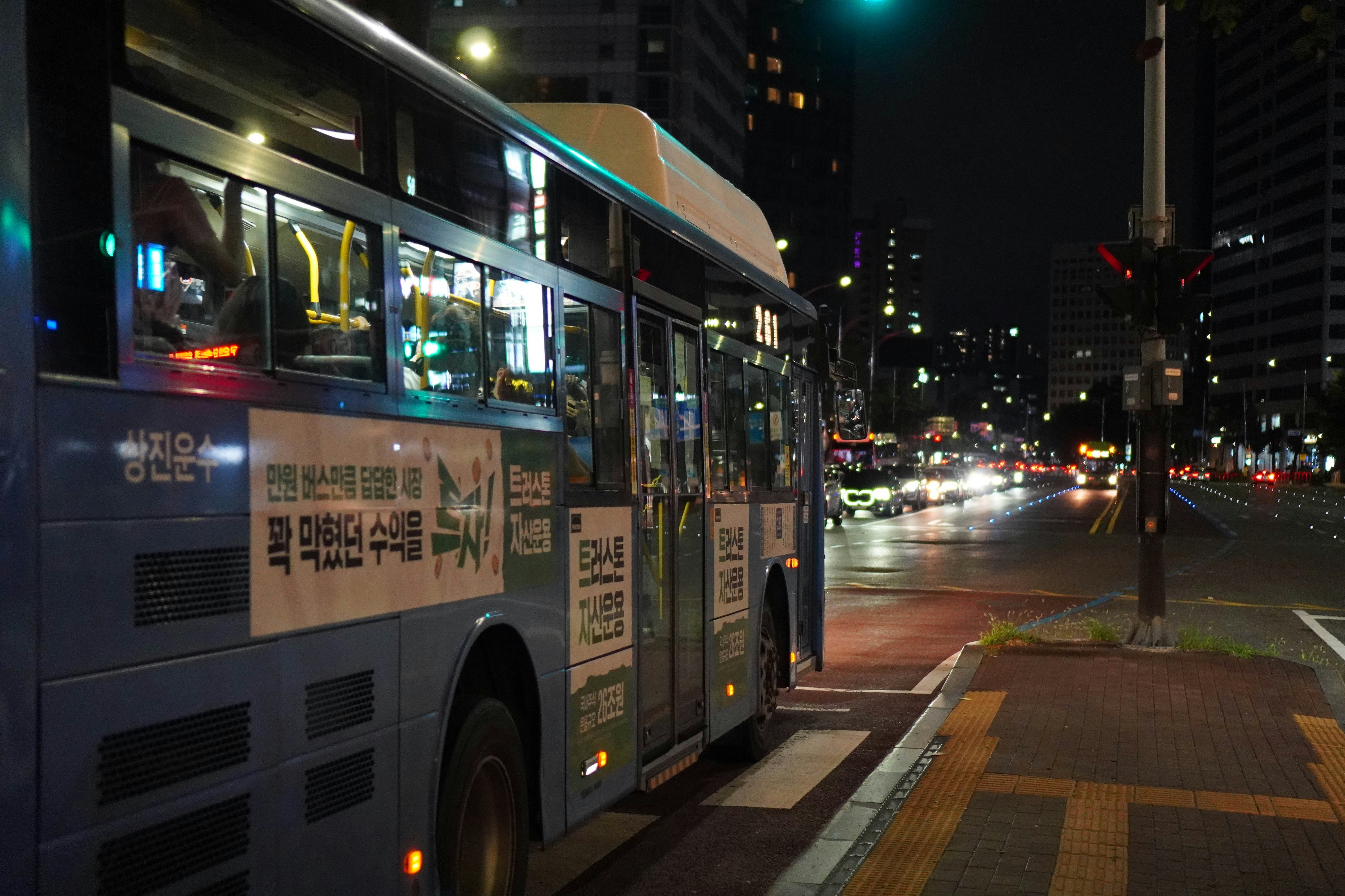 夜の交差点で、信号がぼやけた青い市バス