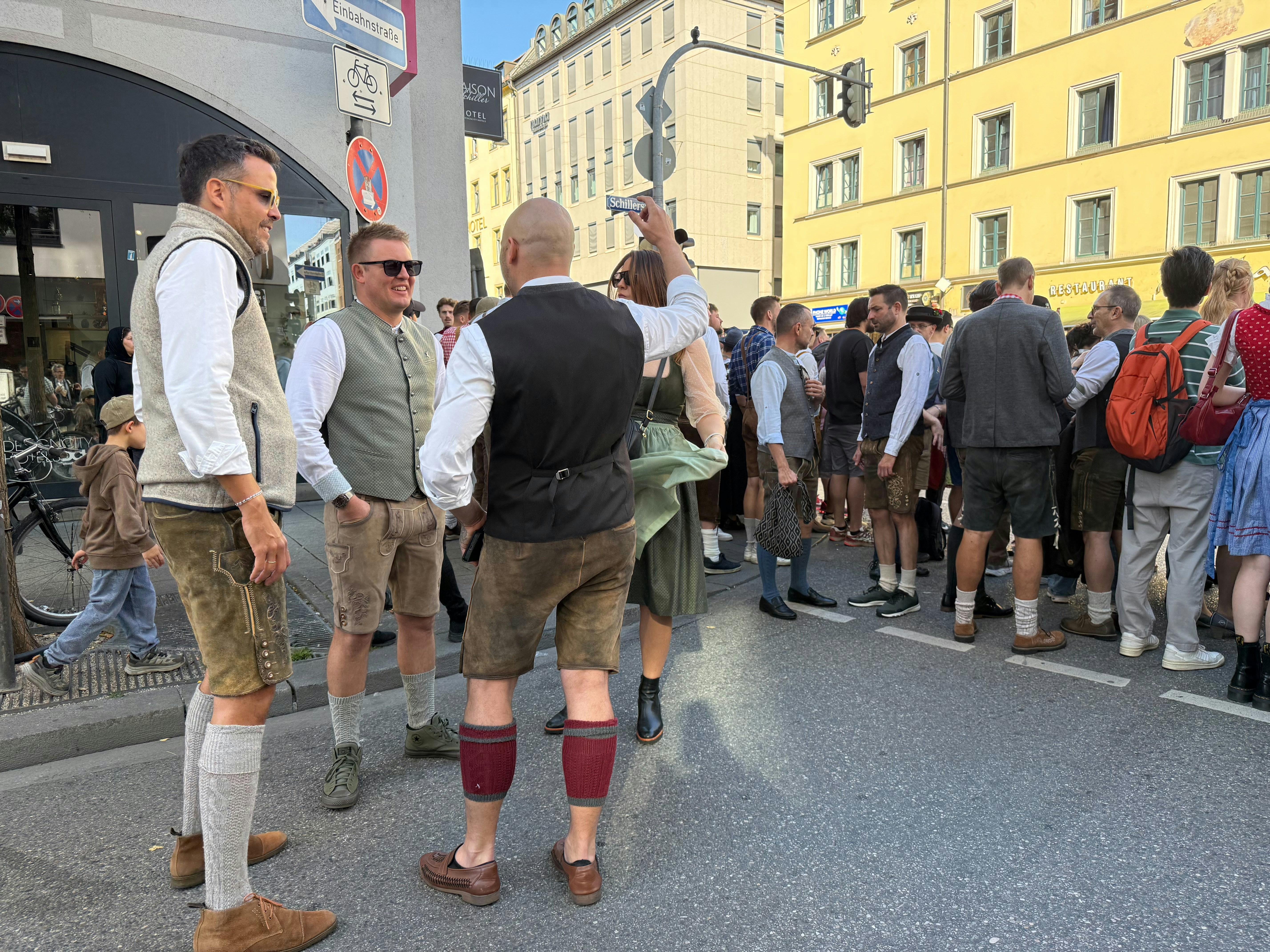 People in traditional Bavarian clothing standing on a city street during a festival