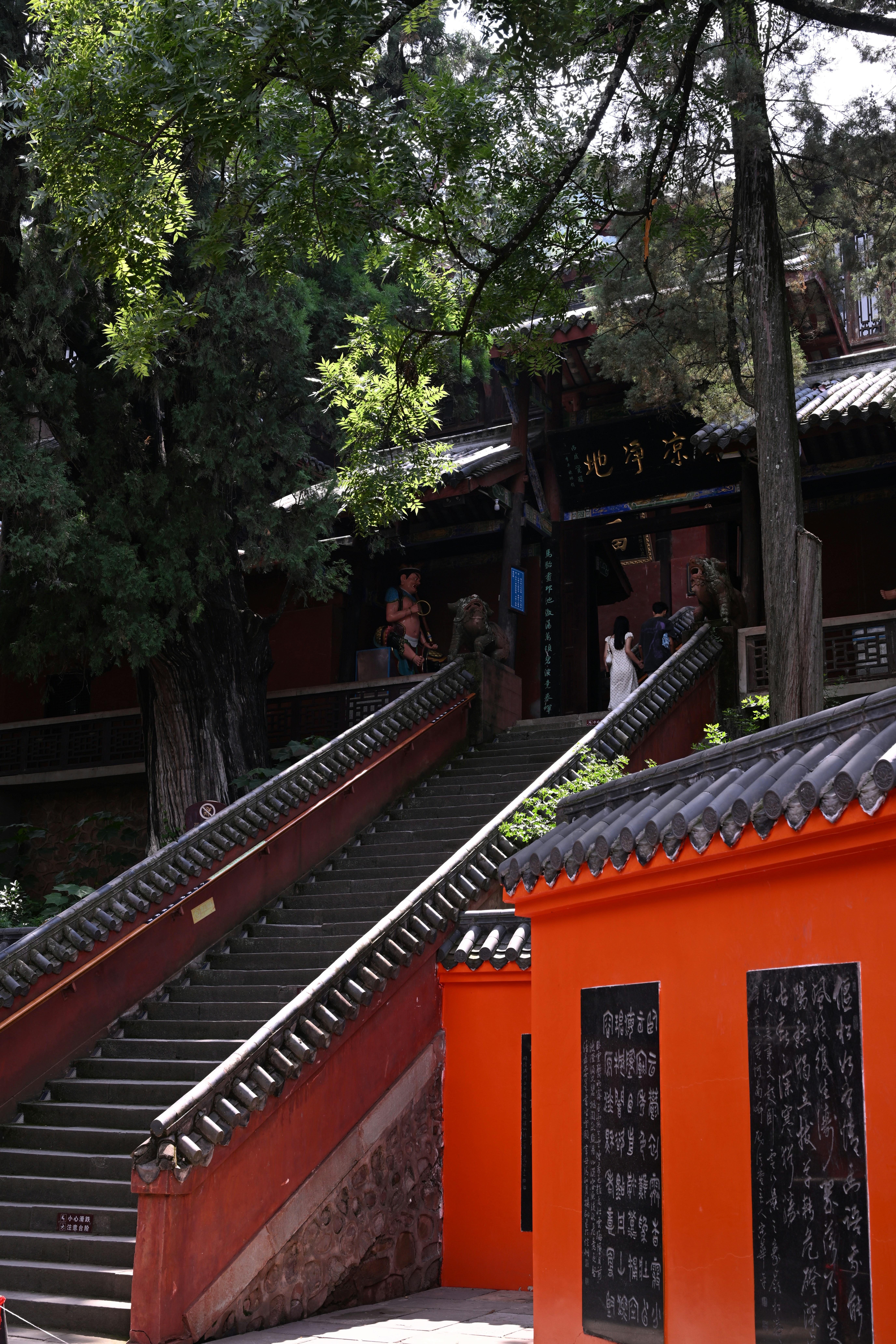 Stone stairs leading to a traditional temple entrance with orange walls and trees