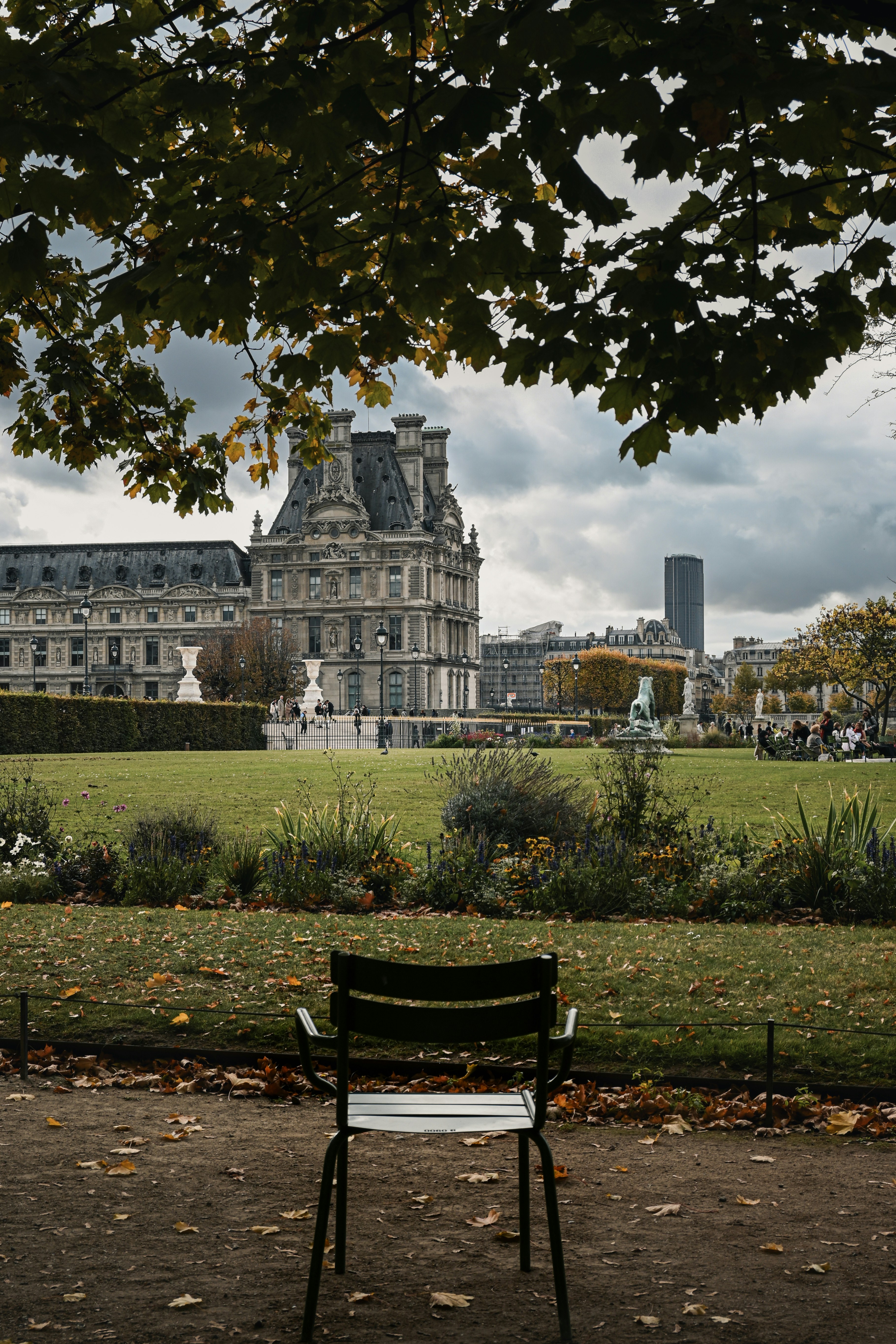 A metal chair in the Tuileries Garden with the Louvre Museum in Paris