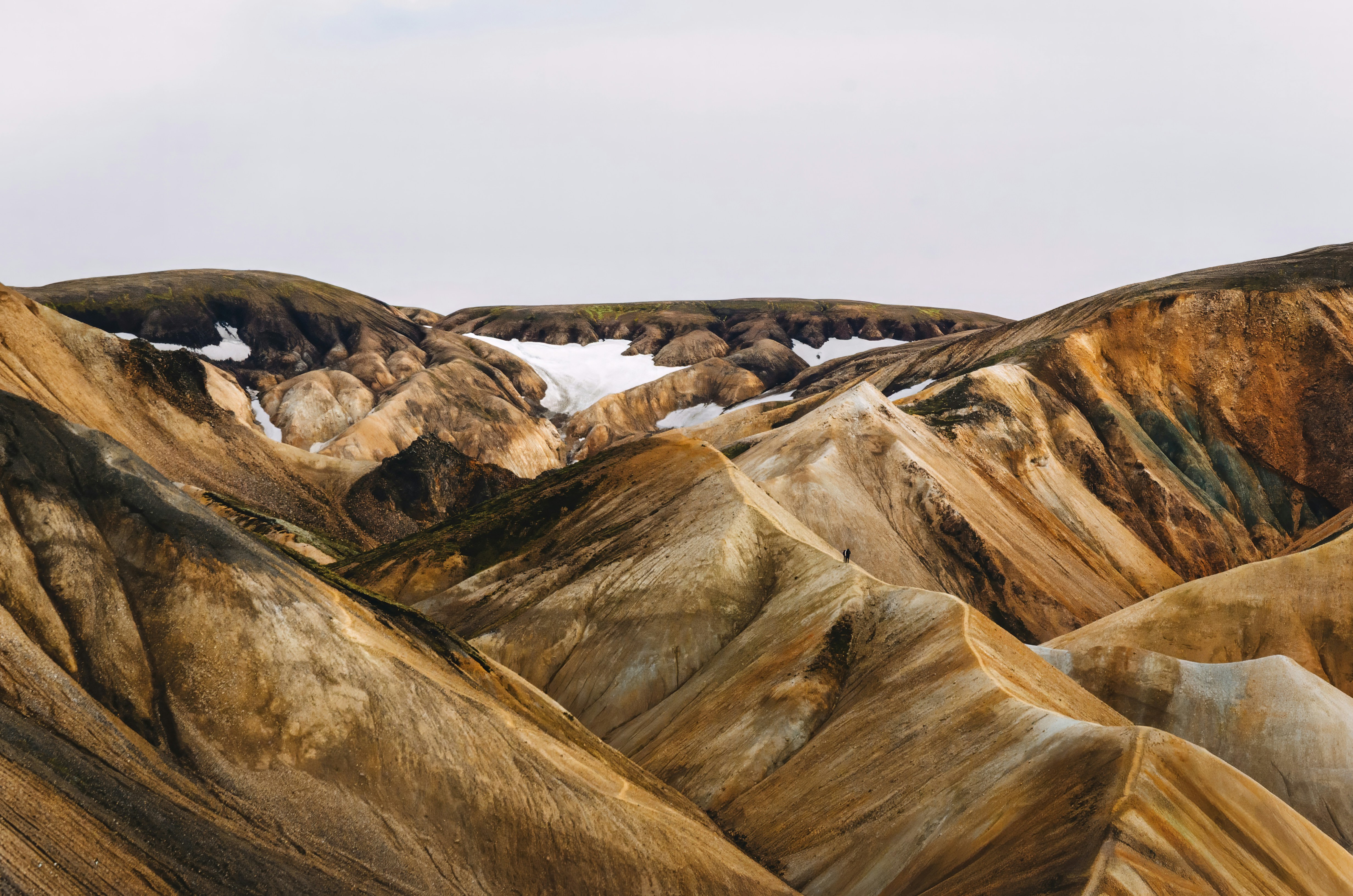 A person walking along a narrow ridge in the colorful rhyolite mountains of Landmannalaugar