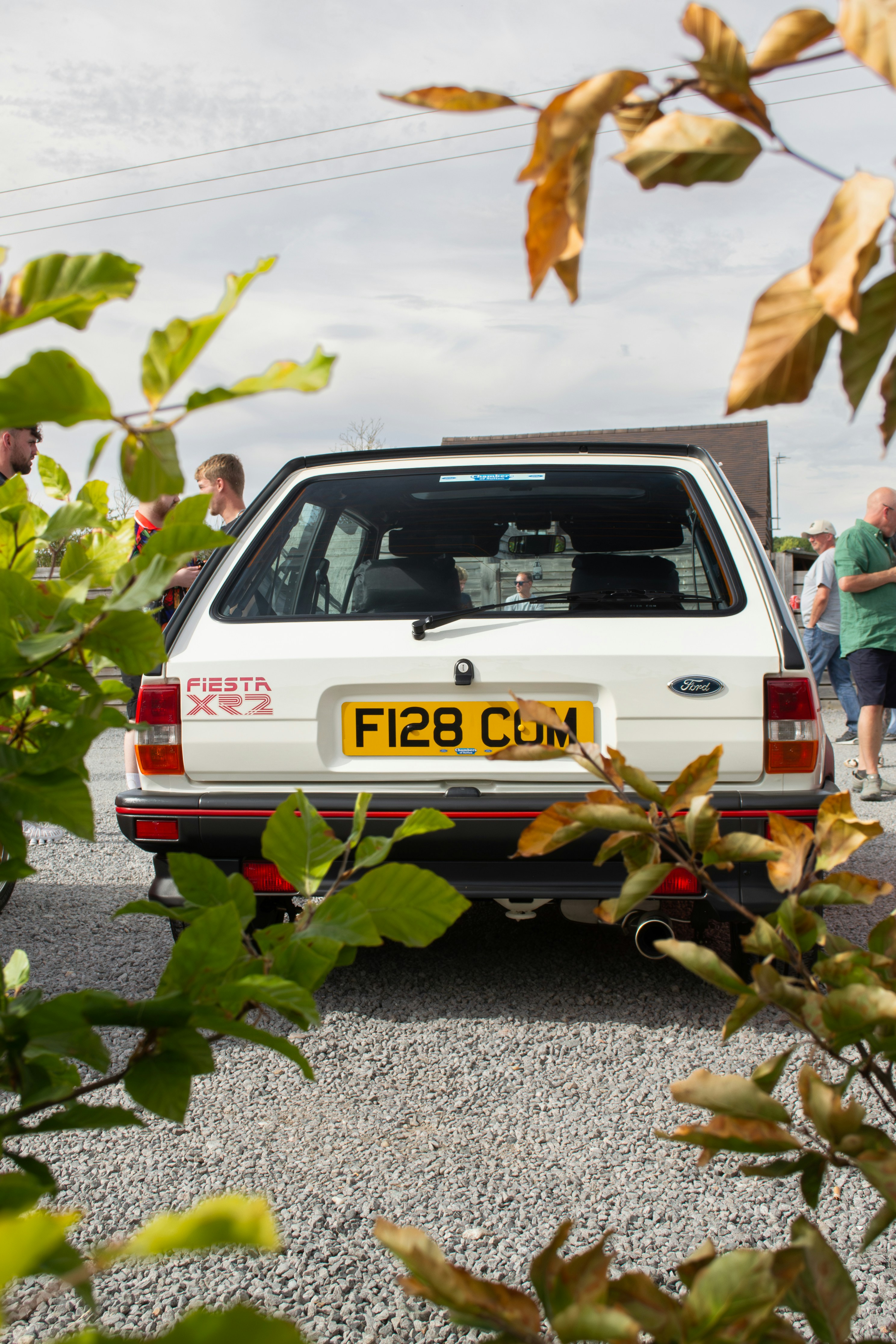Vue arrière d’une Ford Fiesta XR2 blanche garée sur un terrain de gravier