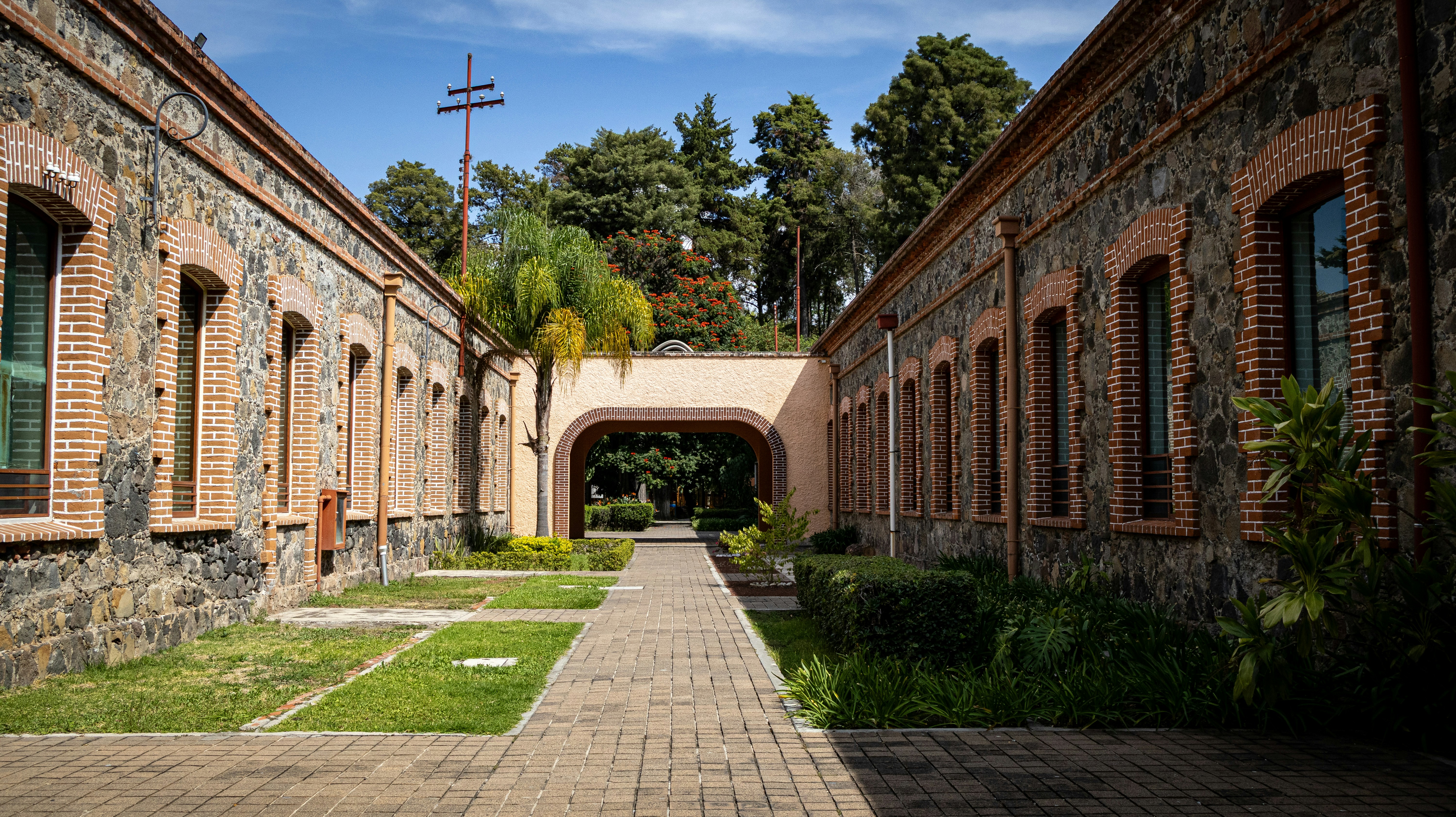 A stone walkway between two brick and stone buildings with arched windows