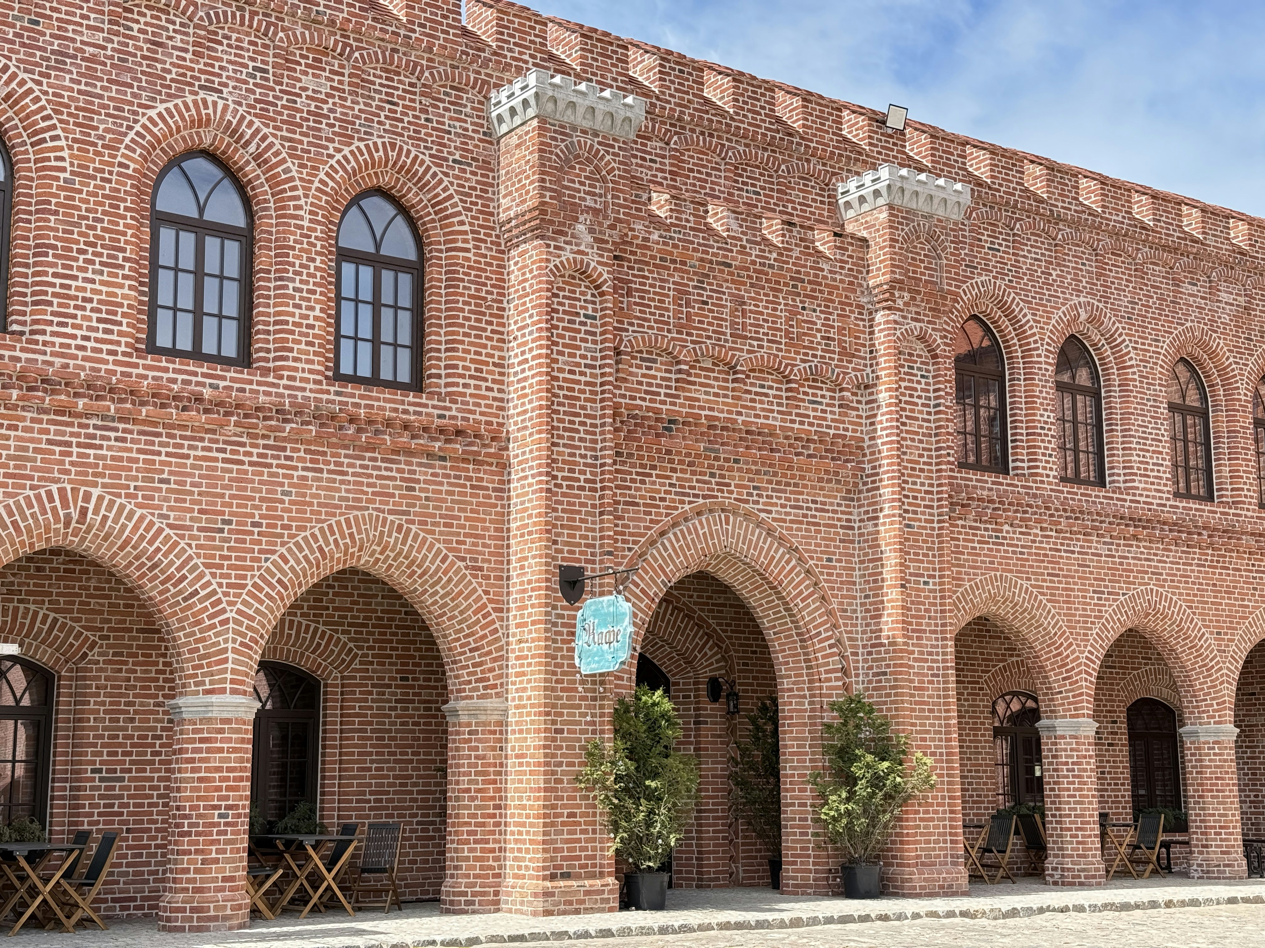 A red brick building with arched windows and a cafe sign above the entrance