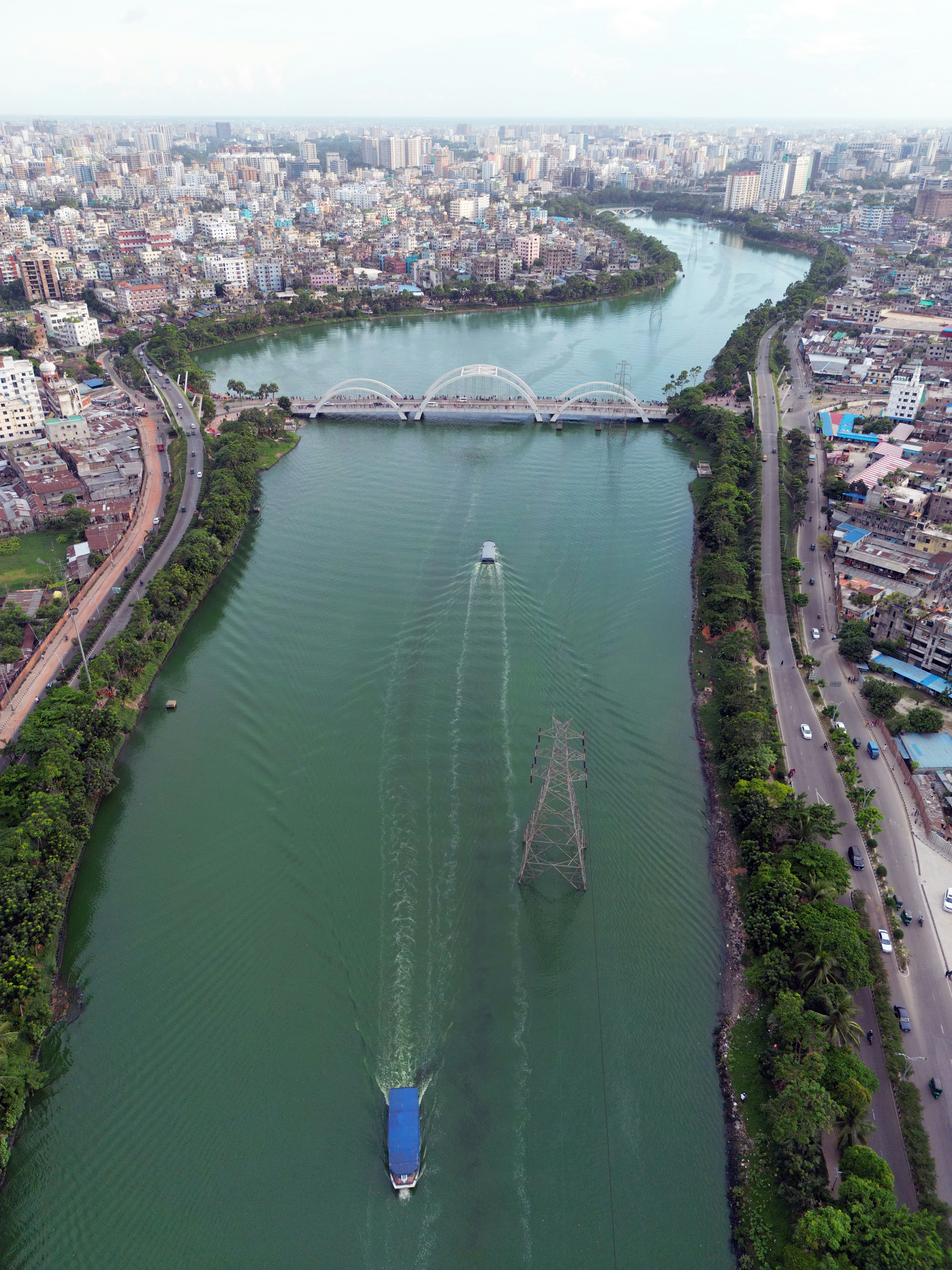 Vista aérea de uma ponte branca com arco sobre um rio verde em Dhaka