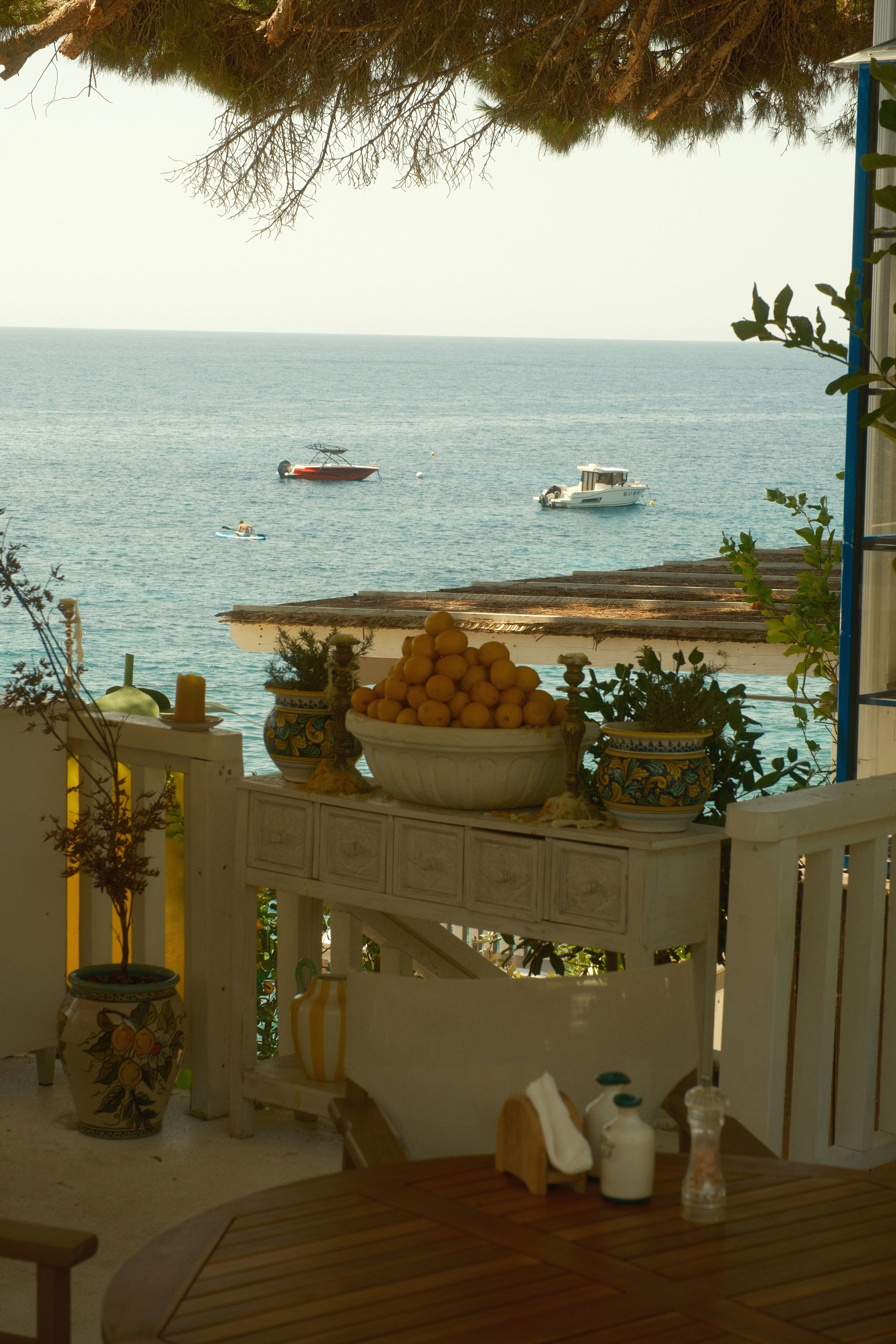A bowl of lemons on a white table overlooking the blue sea