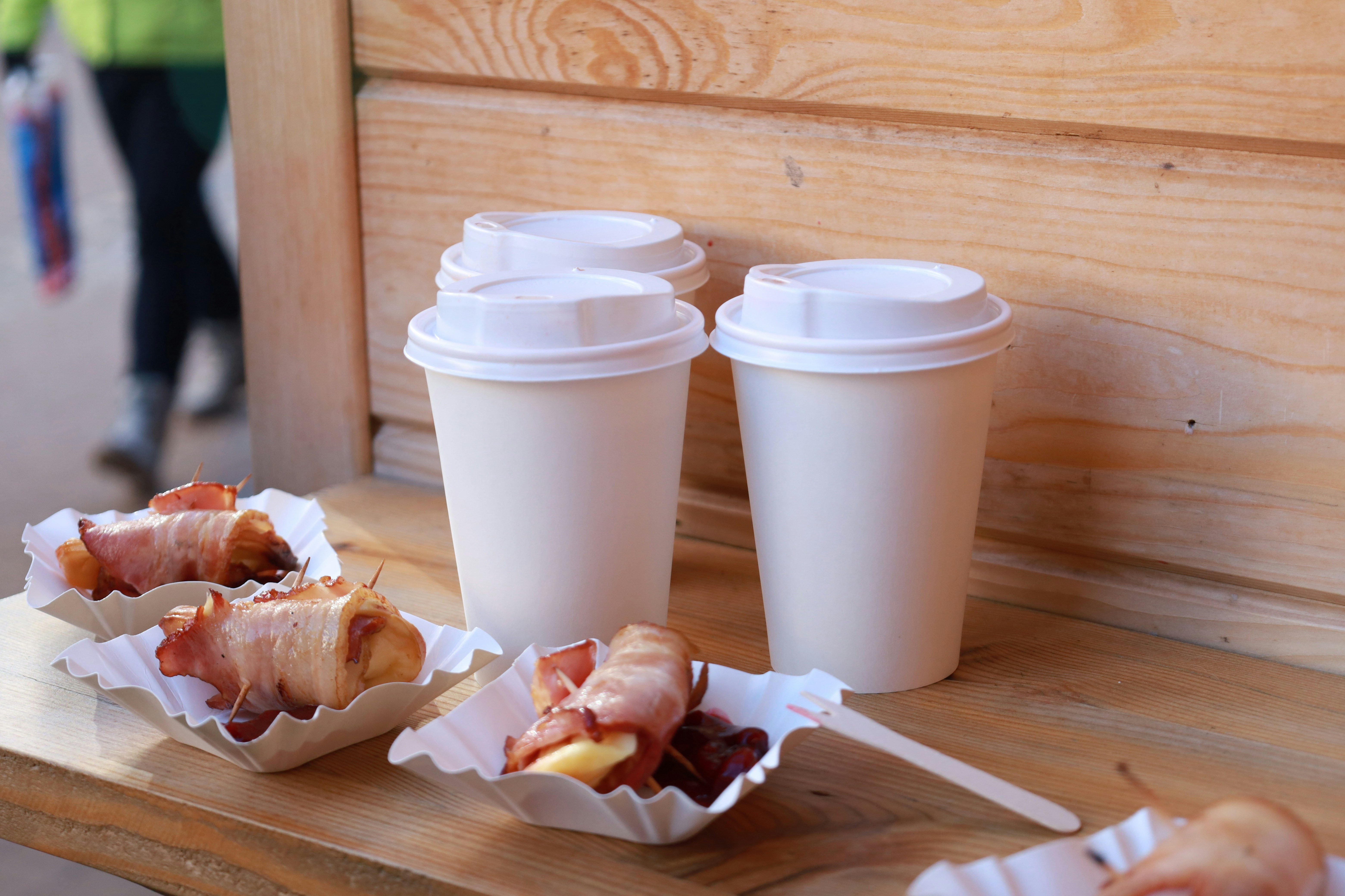 Paper cups and bacon wraps on a wooden bench