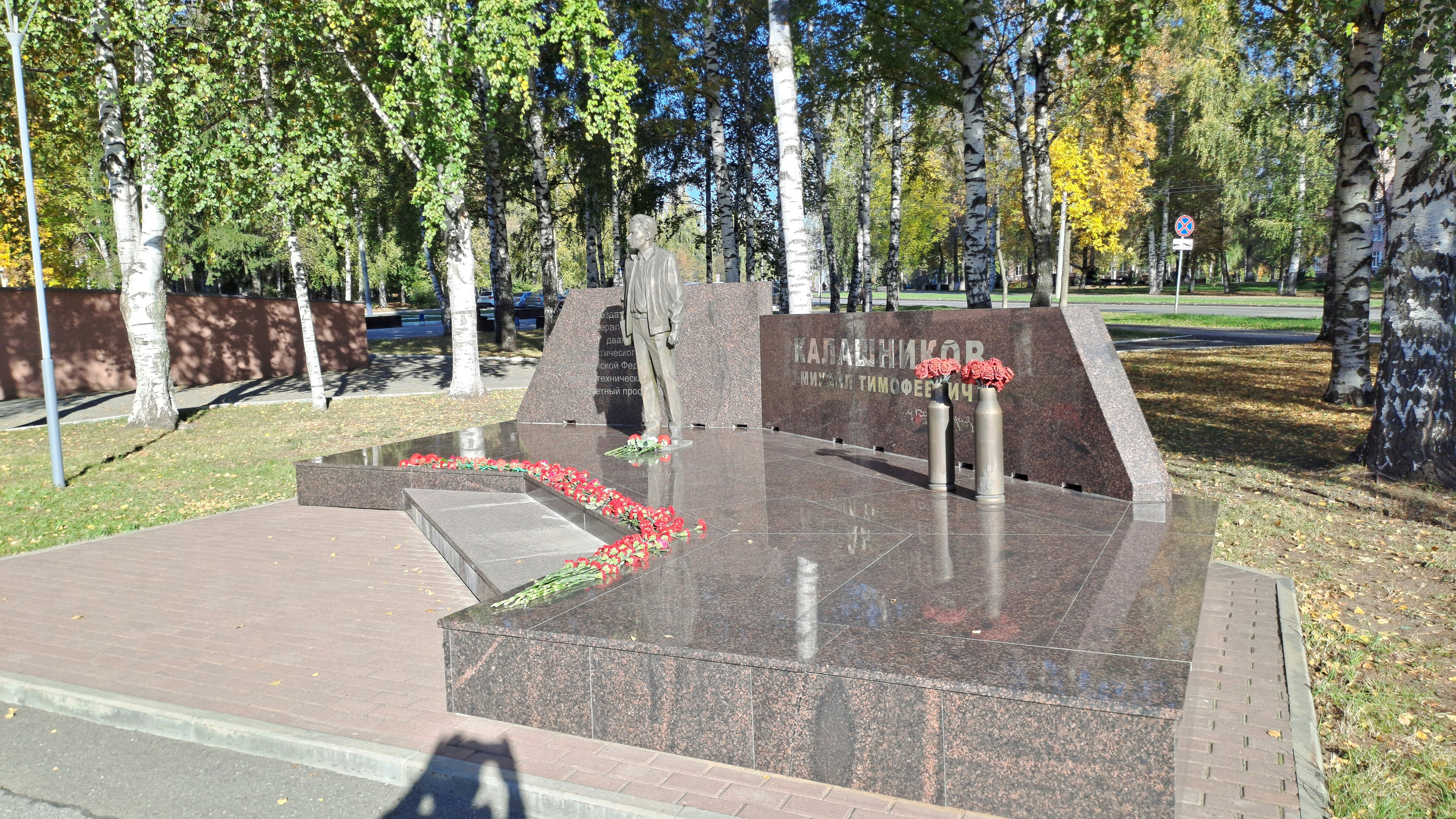 Estatua de bronce sobre un monumento de granito con flores - Foto ...