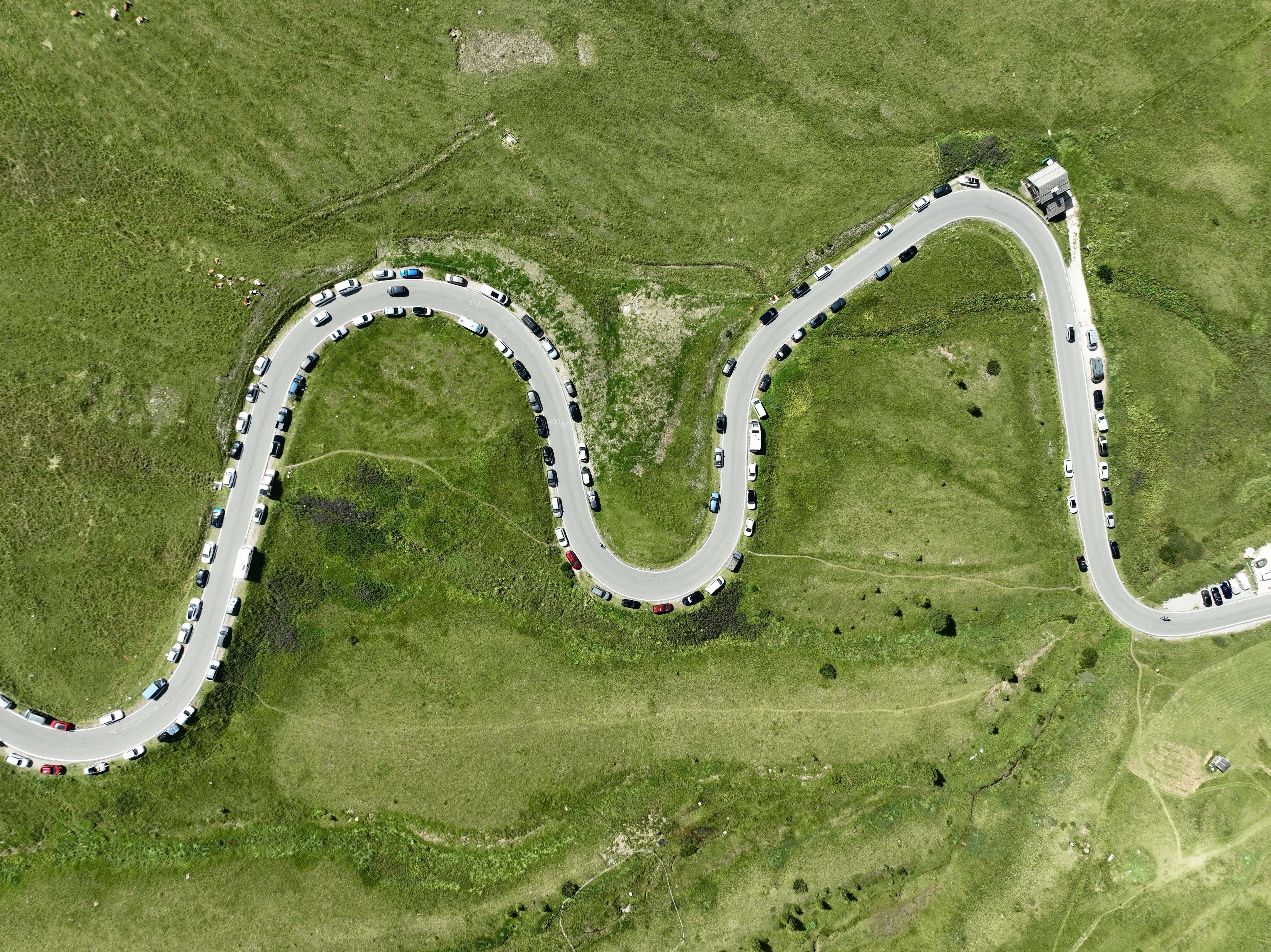 Vista aérea de una carretera de montaña sinuosa bordeada de coches aparcados