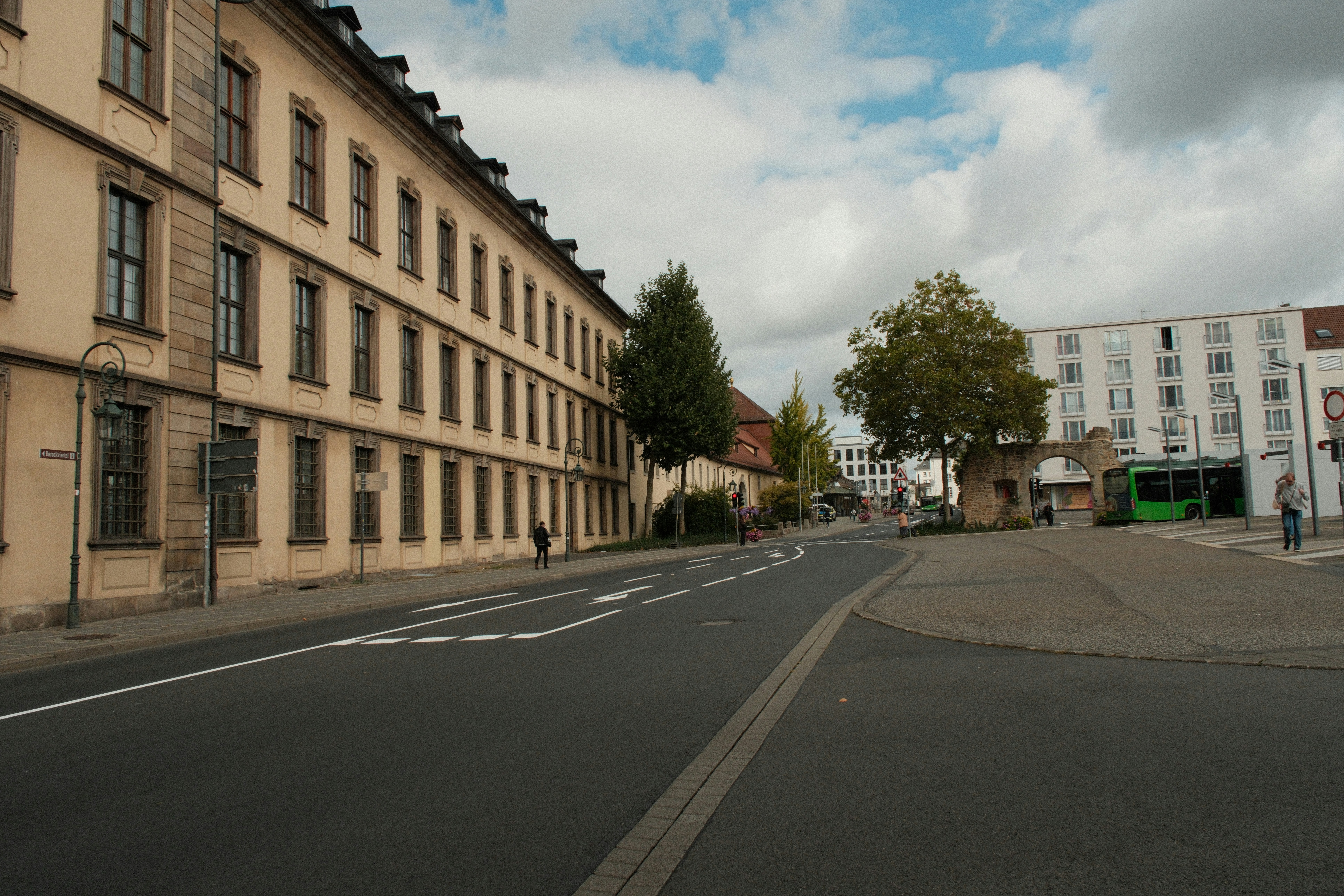 A historic building with many windows beside a road and stone archway