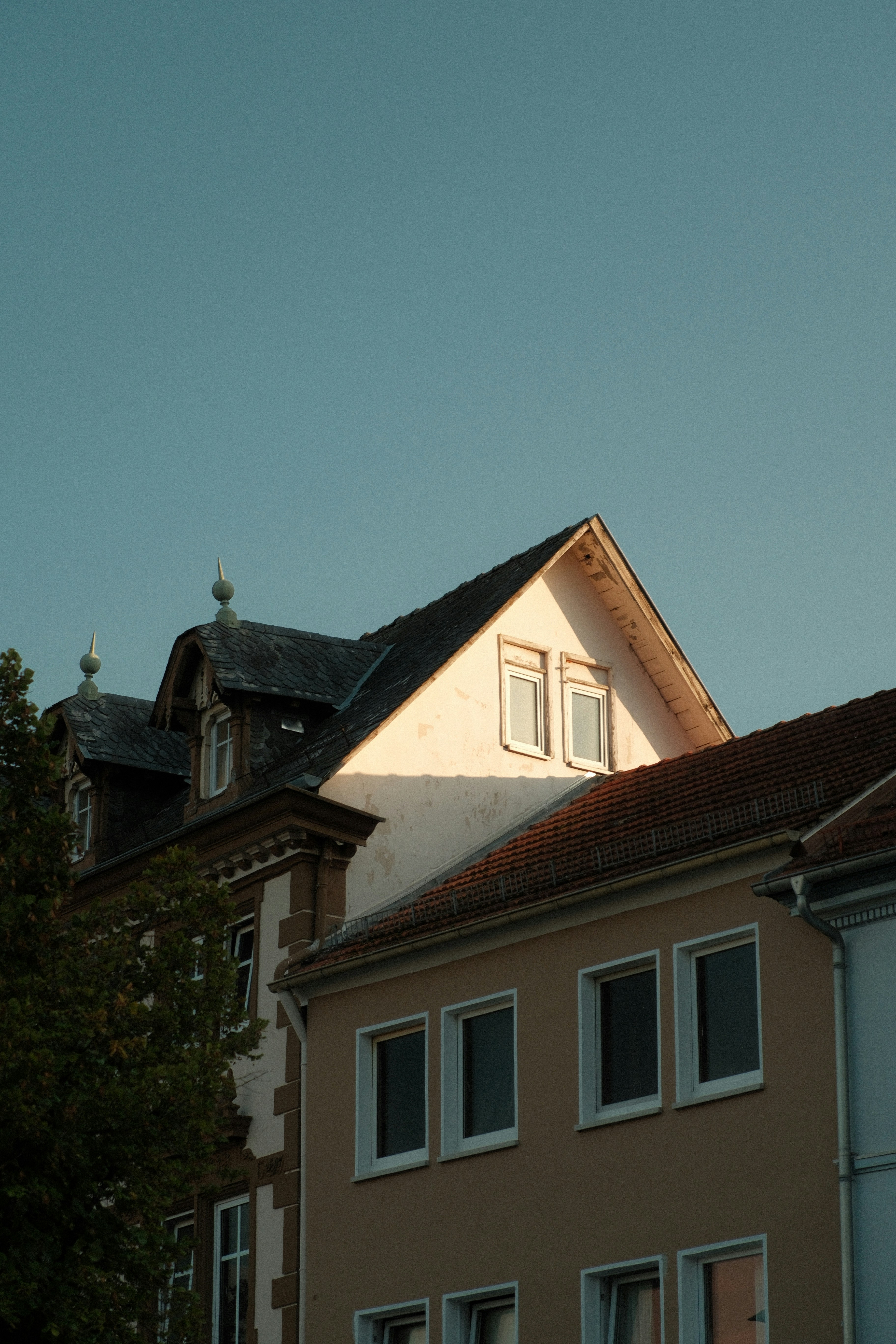 A gabled roof and dormers on a building facade under a clear blue sky