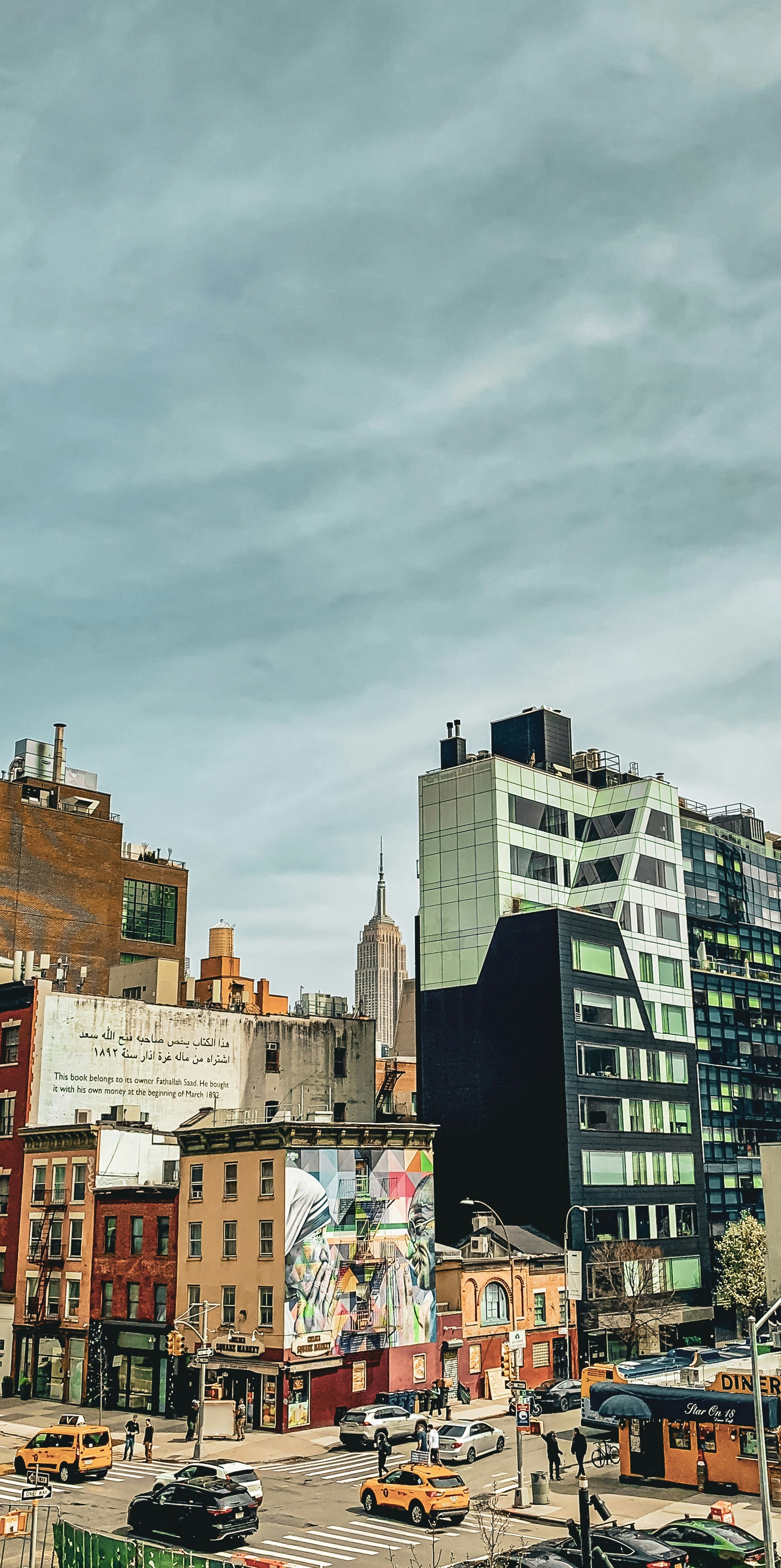 The Empire State Building rising above a New York City street intersection with murals