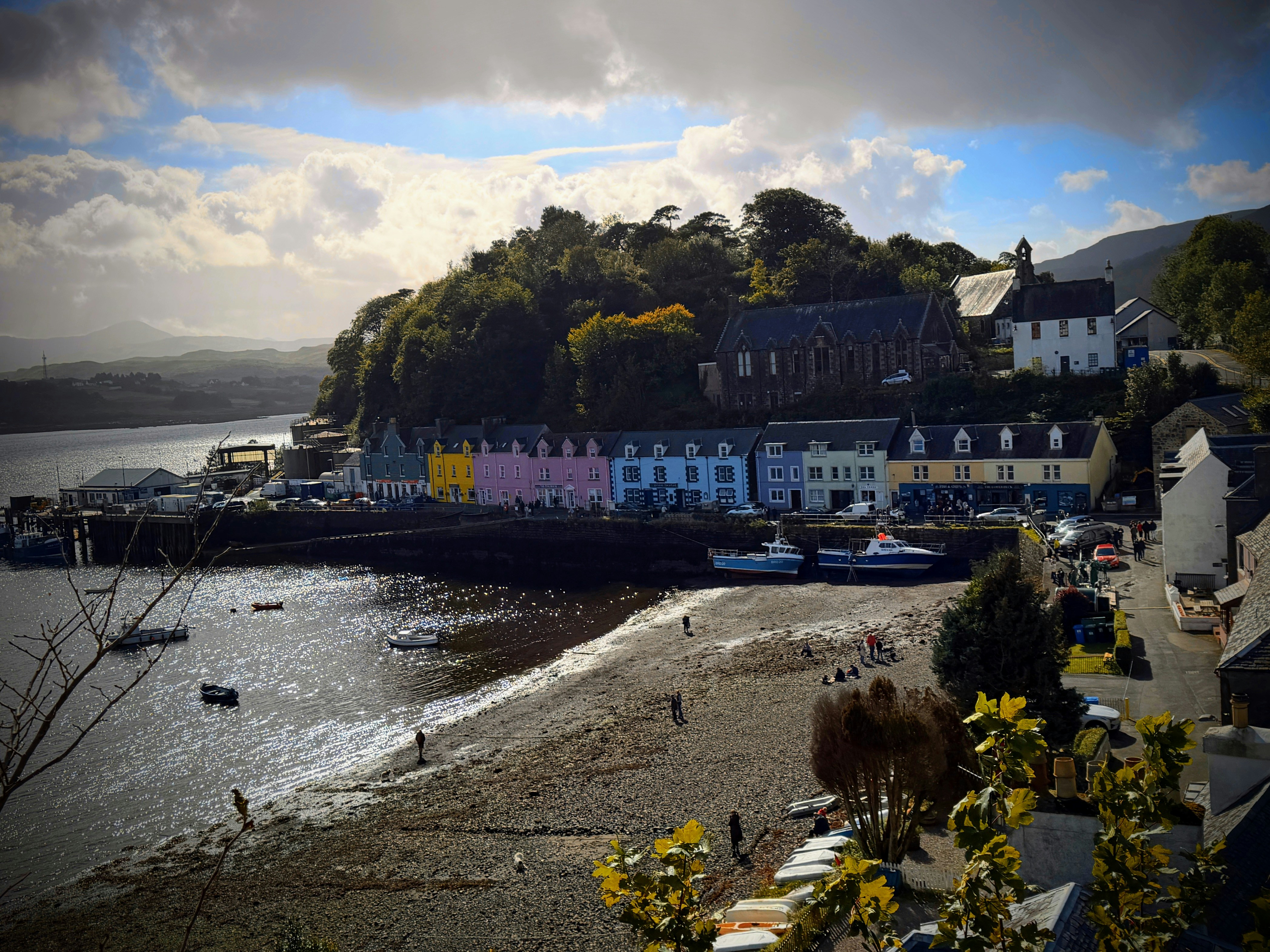 Colorful houses along a harbor with boats on a pebbled beach in Portree