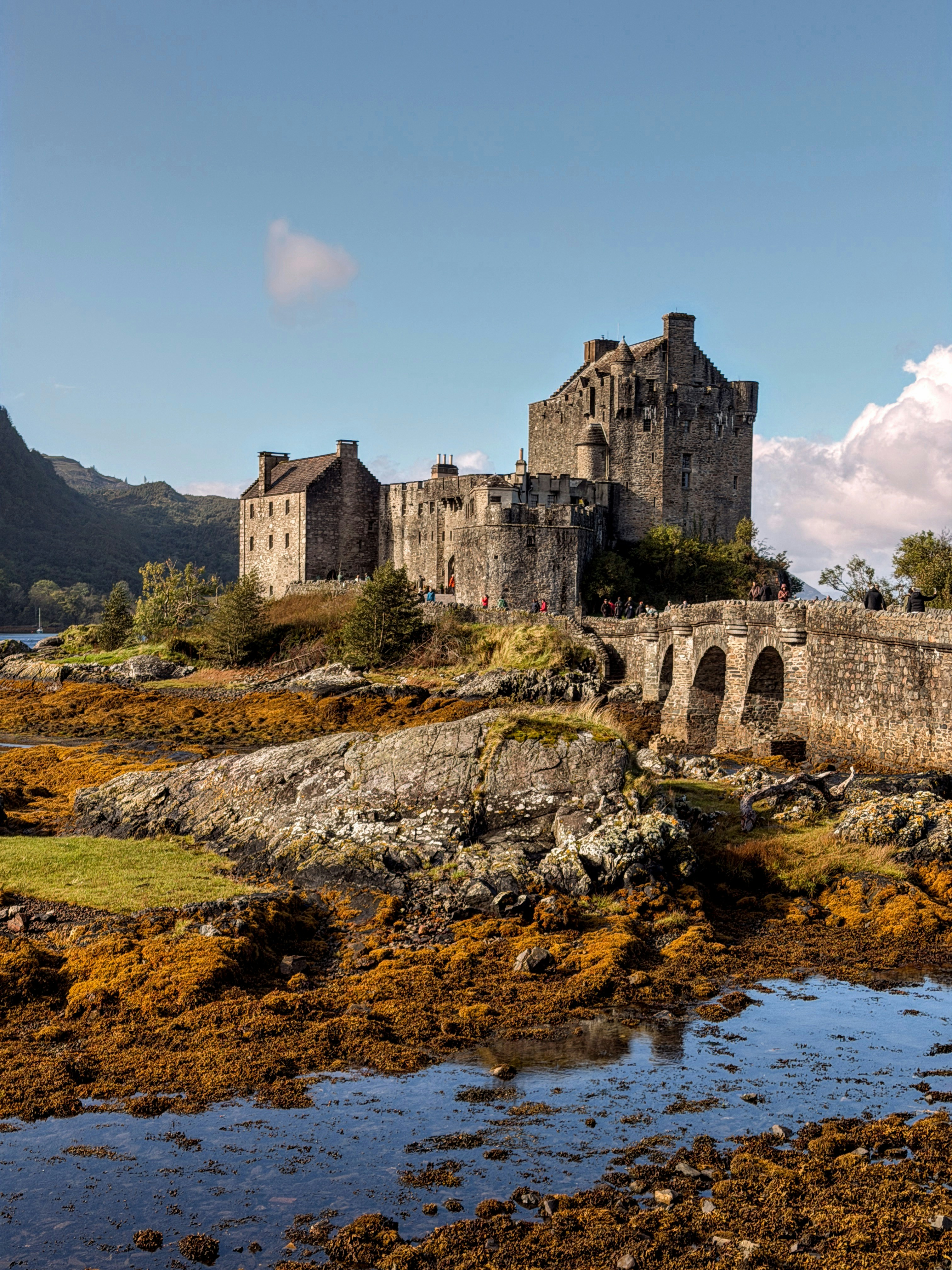 Eilean Donan Castle with its stone bridge over a rocky tidal shore in Scotland