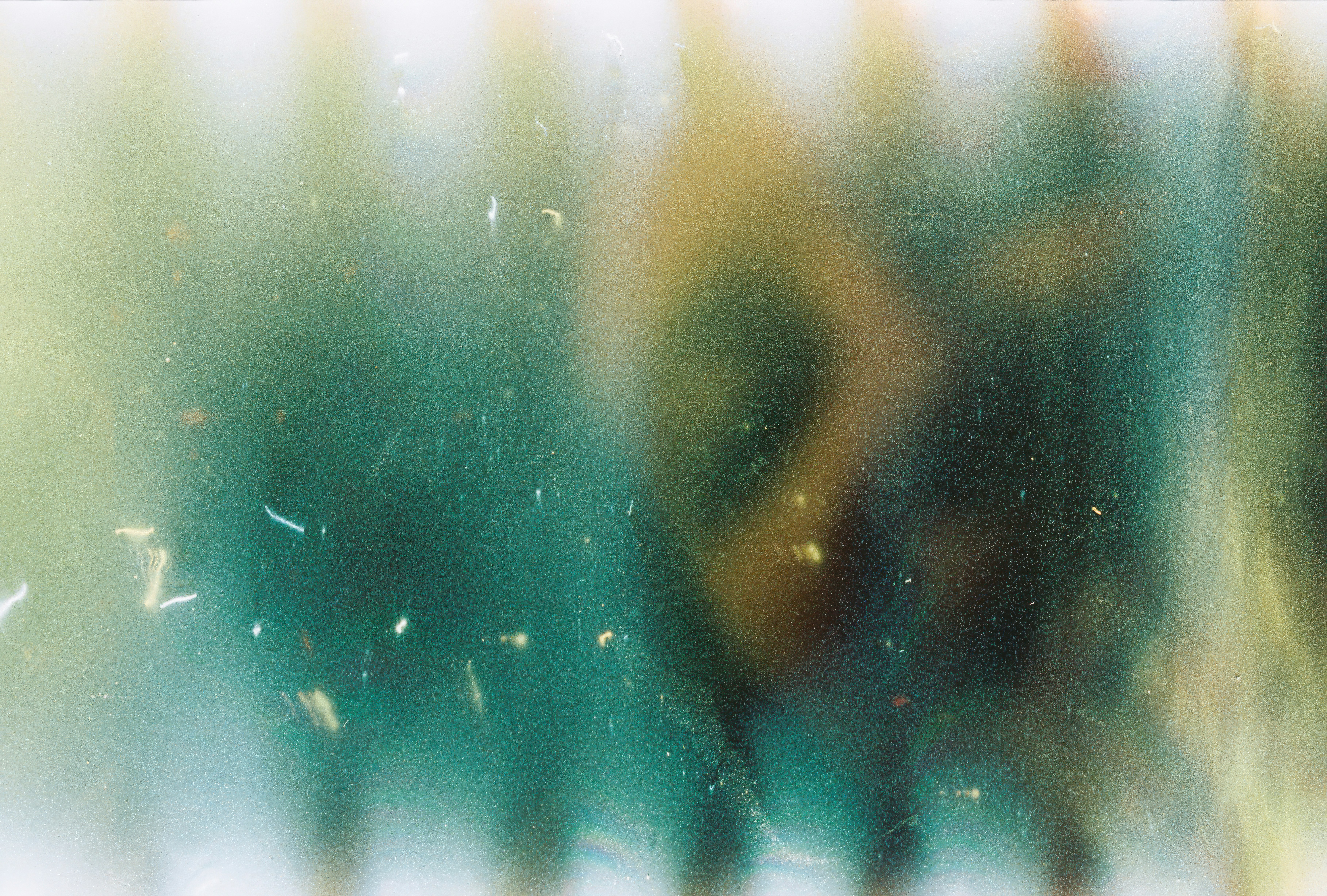 A textured abstract gradient of deep green and warm golden light