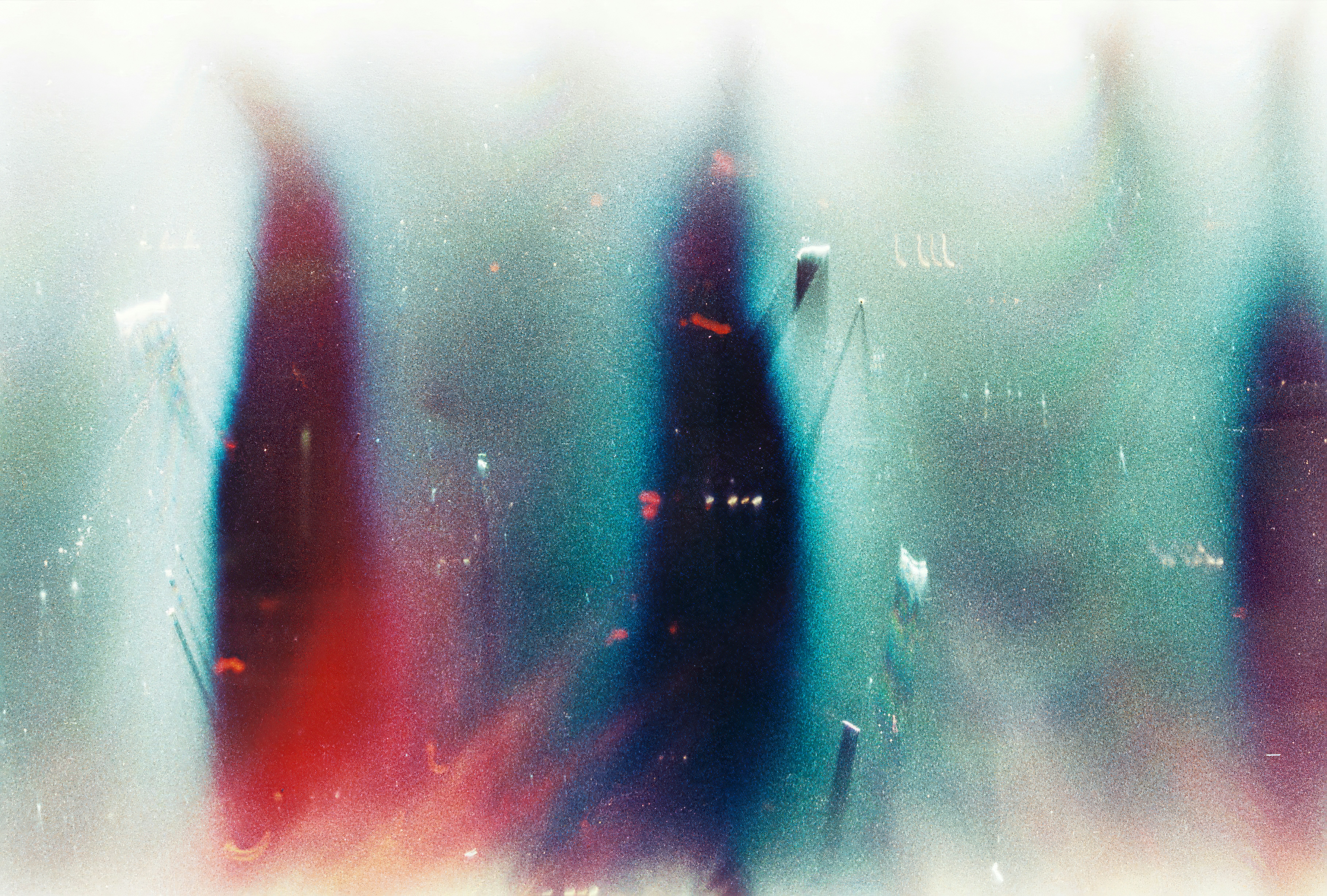 Abstract light streaks in shades of teal, red, and blue with grainy texture