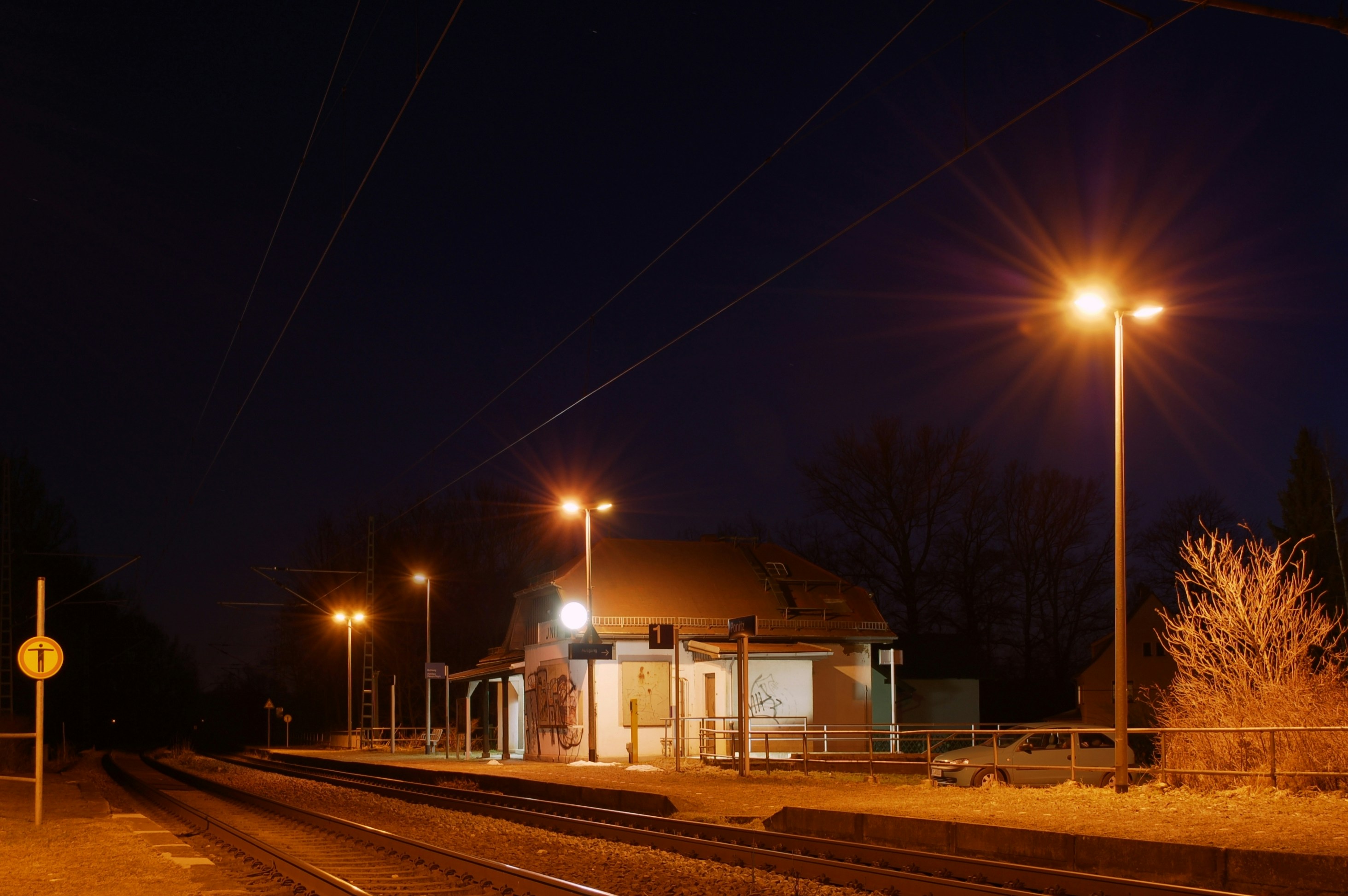 Un quai de gare éclairé par des lampadaires vivs la nuit