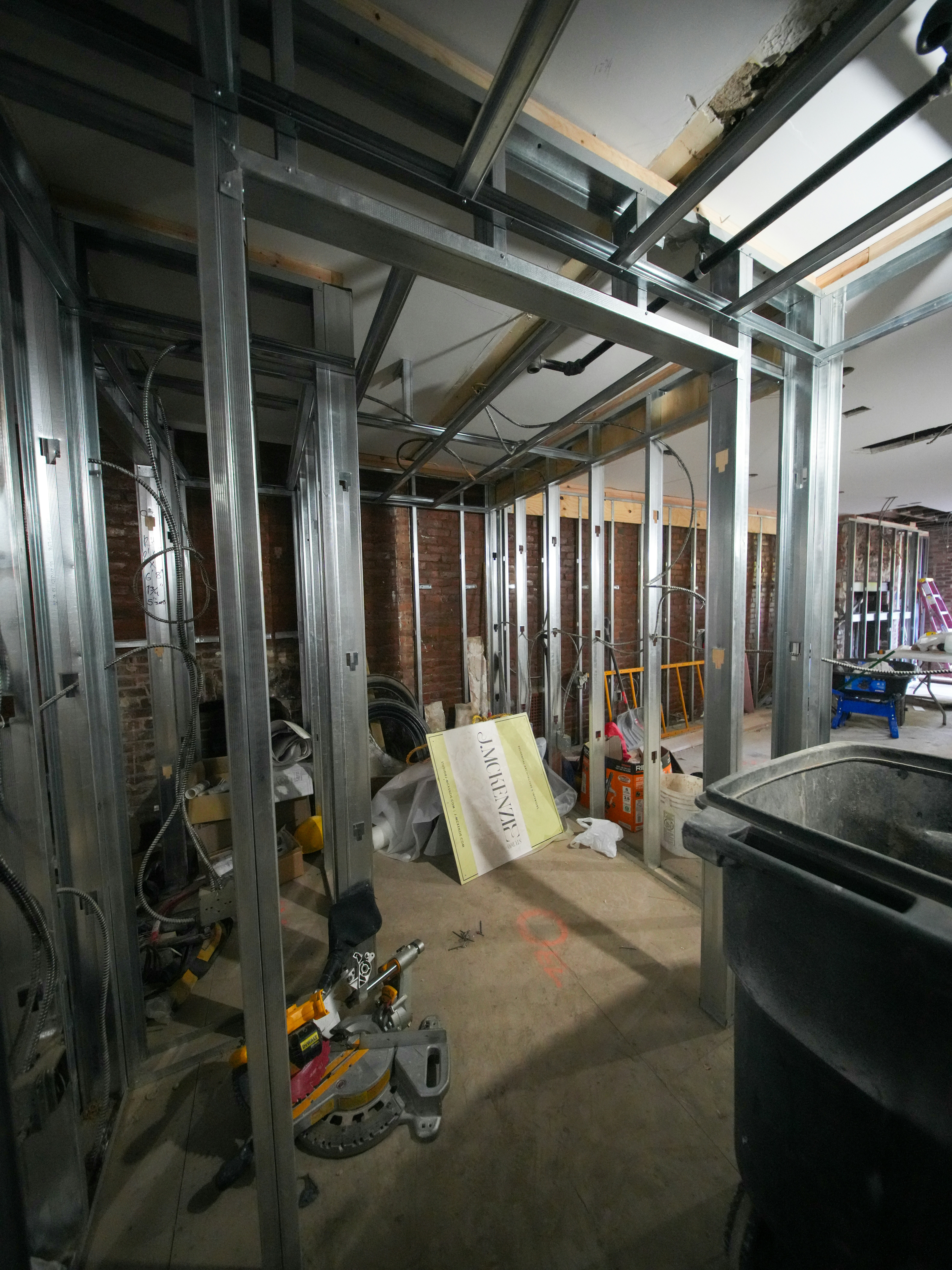 Metal wall studs in a room under construction with exposed brick walls