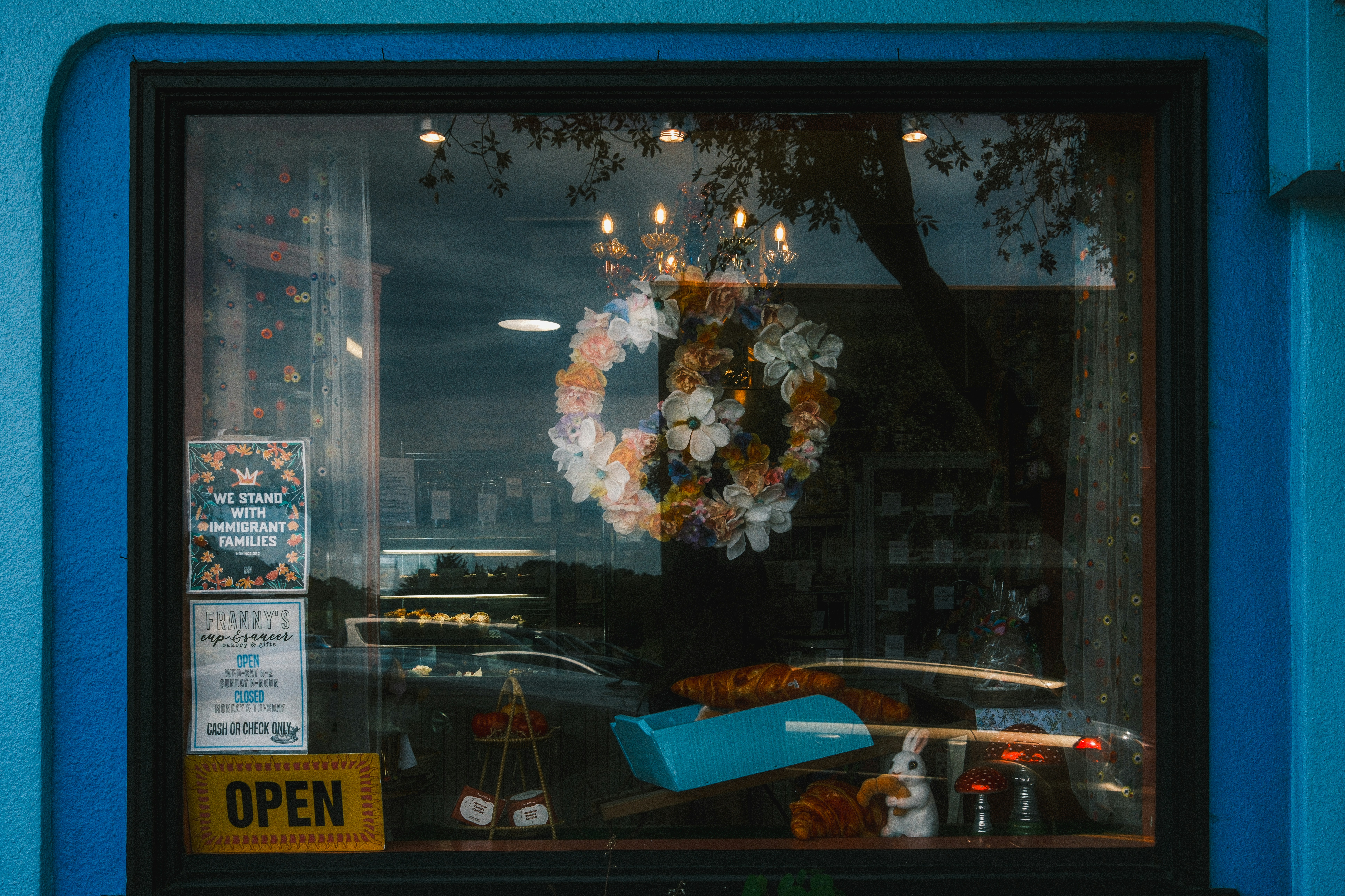 A peace sign wreath made of flowers in a bakery window with pastries