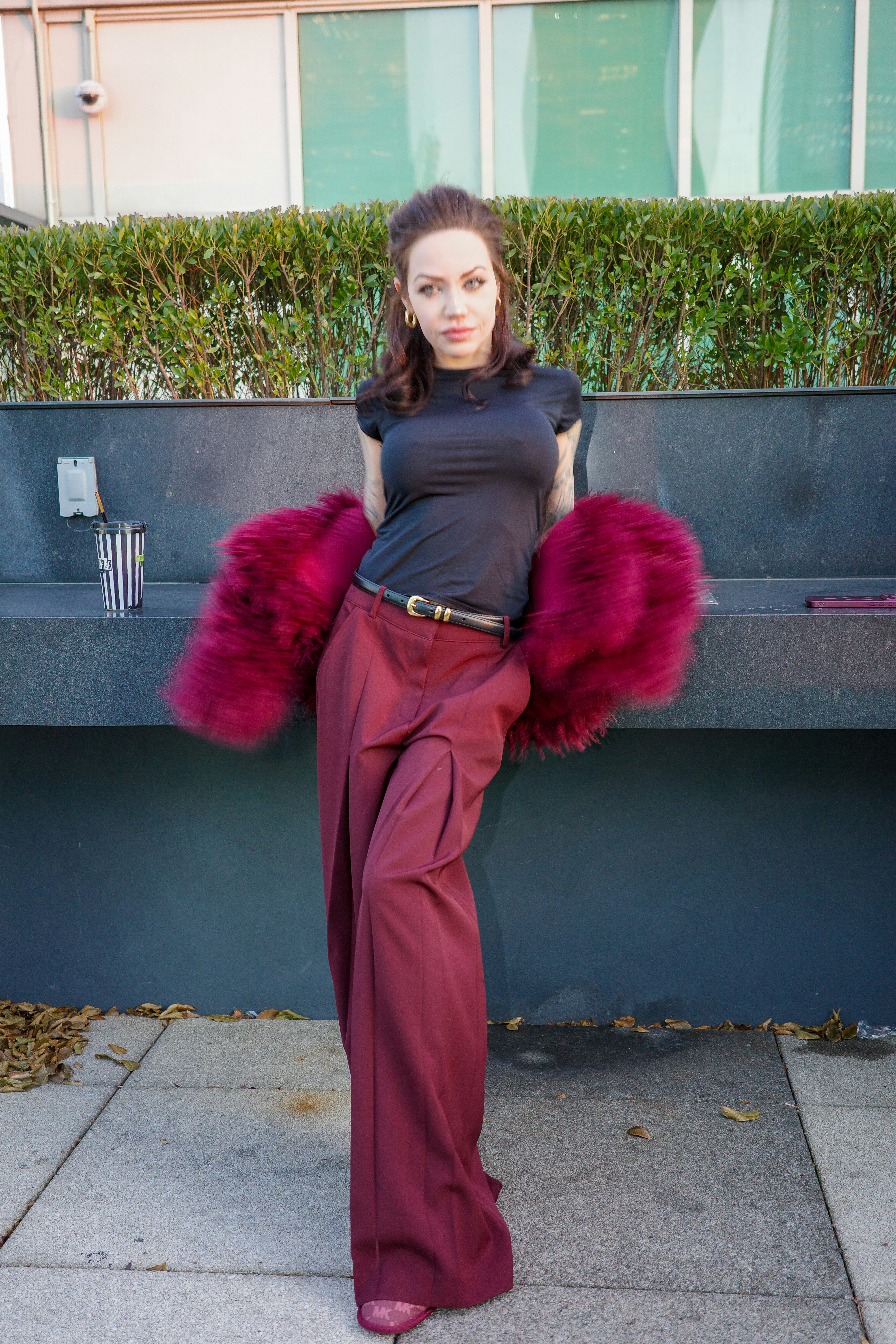 A woman in a black t-shirt and burgundy trousers with a faux fur stole