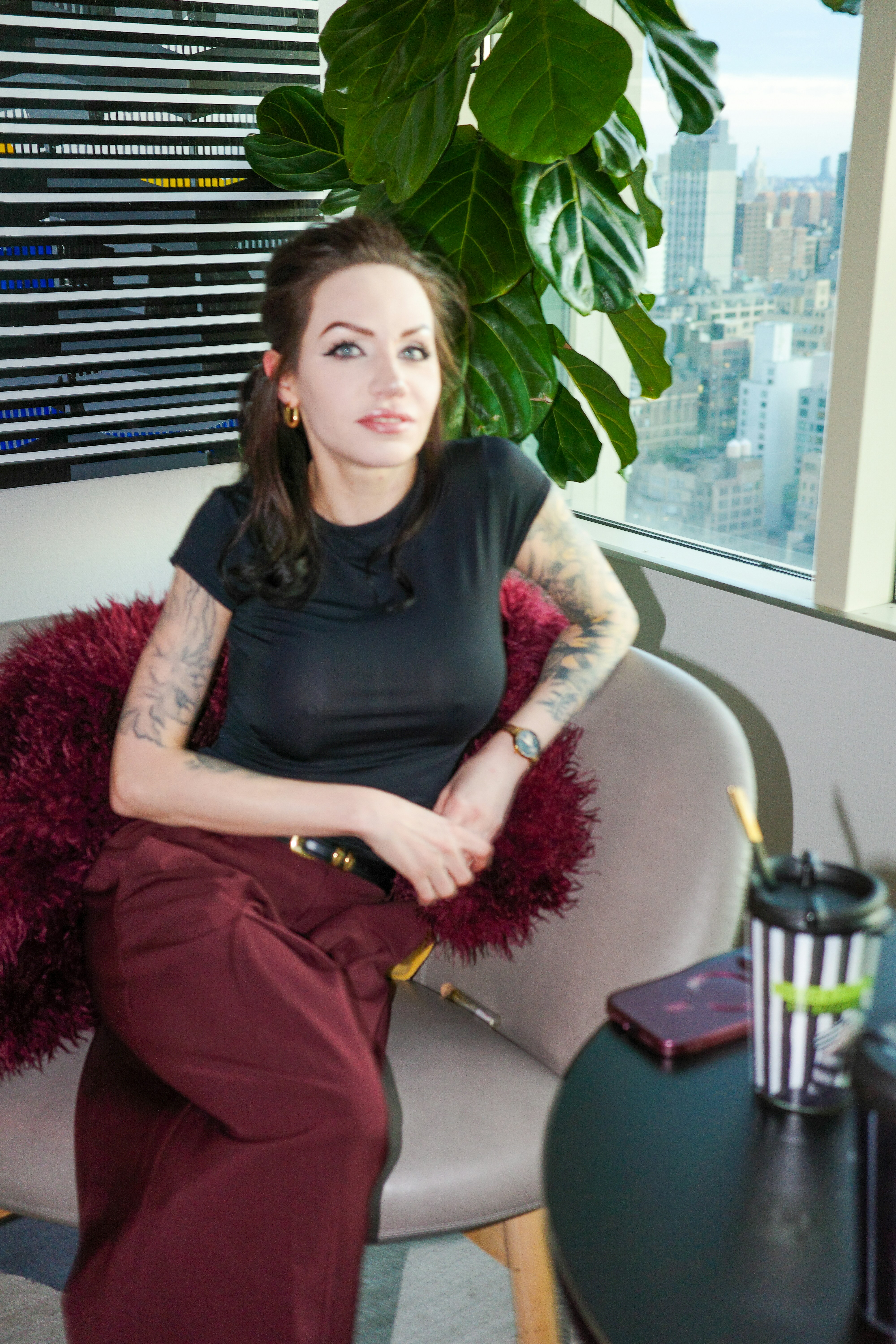 A woman with tattoos in a black t-shirt sitting in a chair