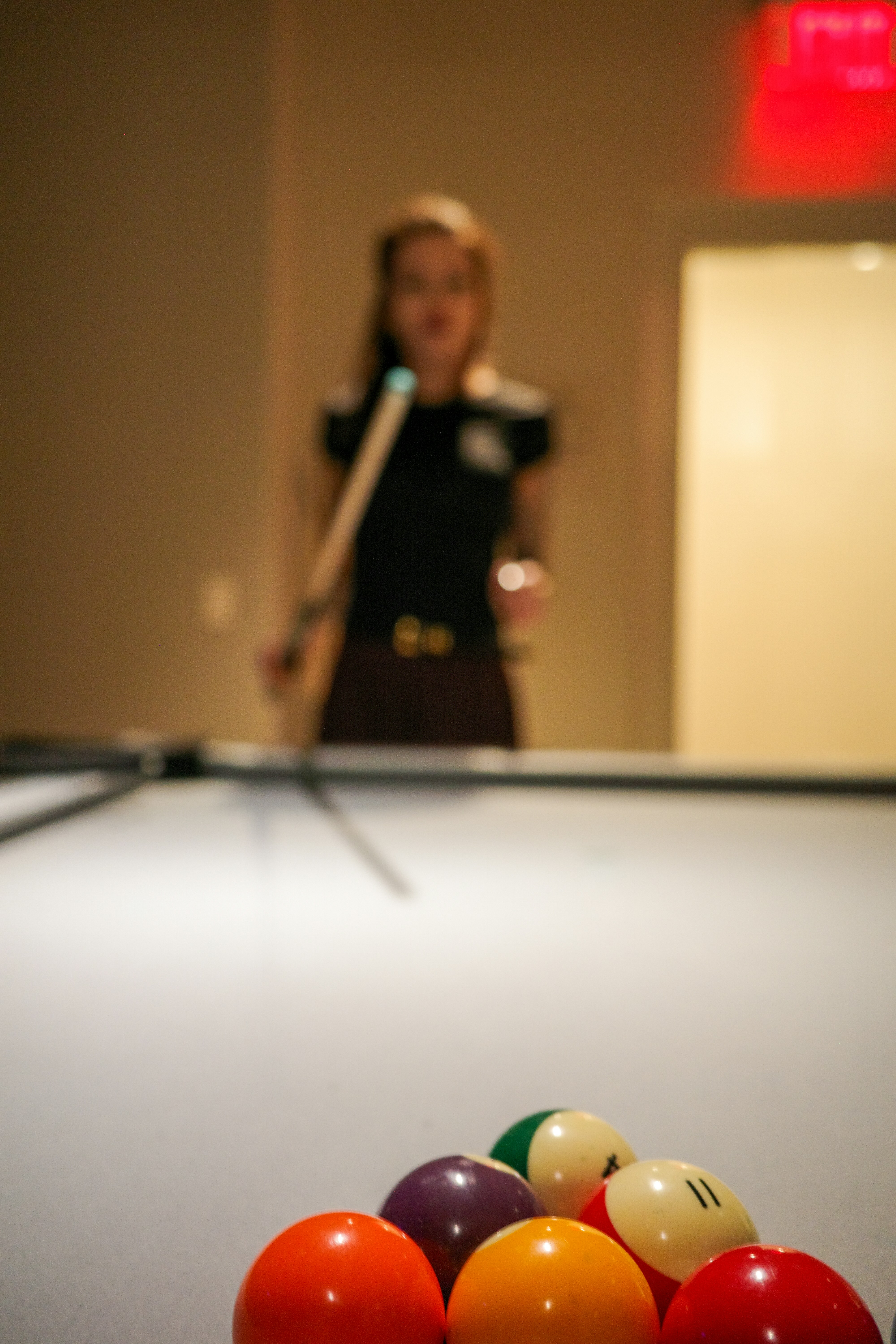 A person holding a pool cue behind a rack of colorful billiard balls