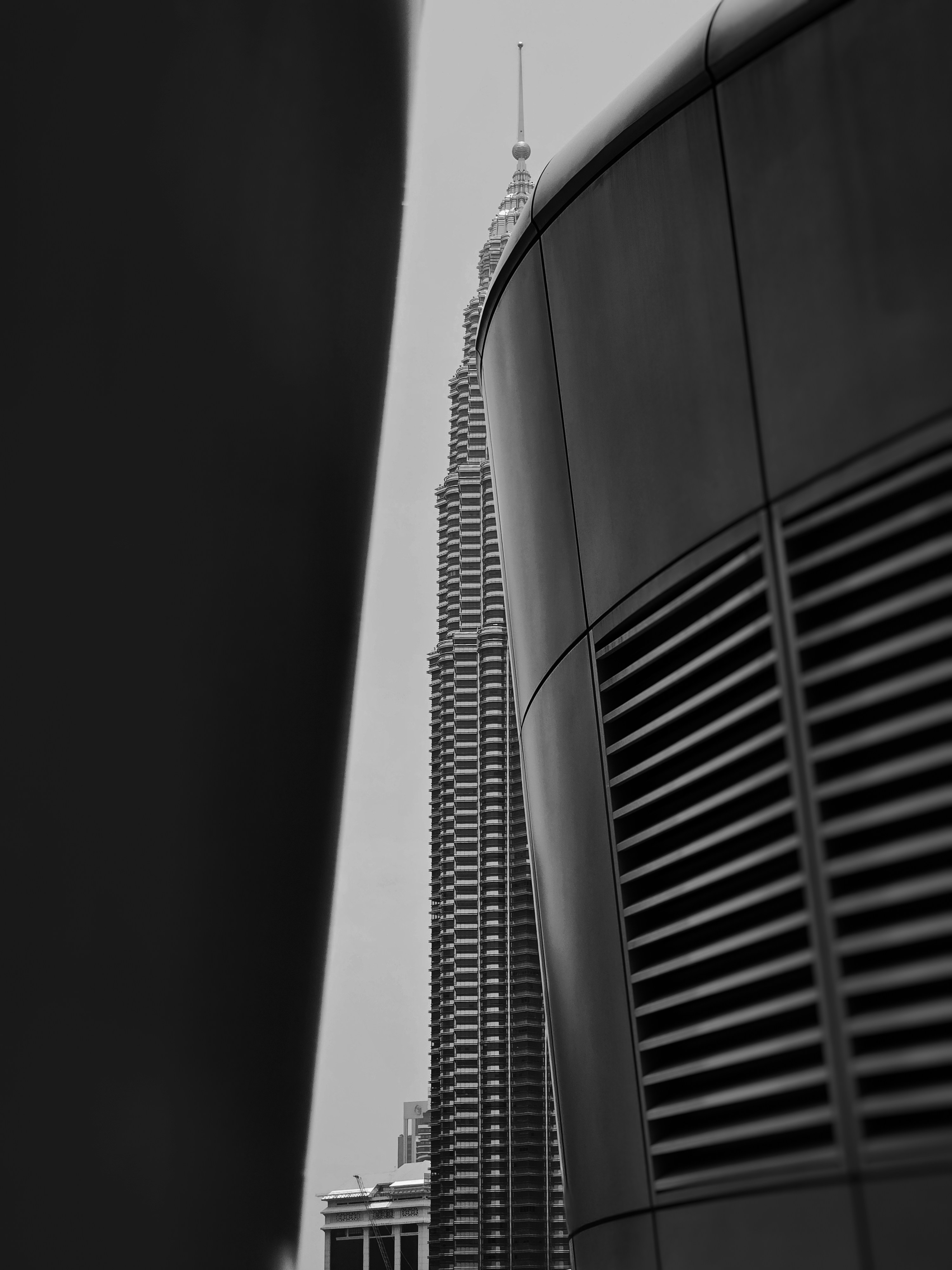 The Petronas Towers framed by dark architectural elements in Kuala Lumpur