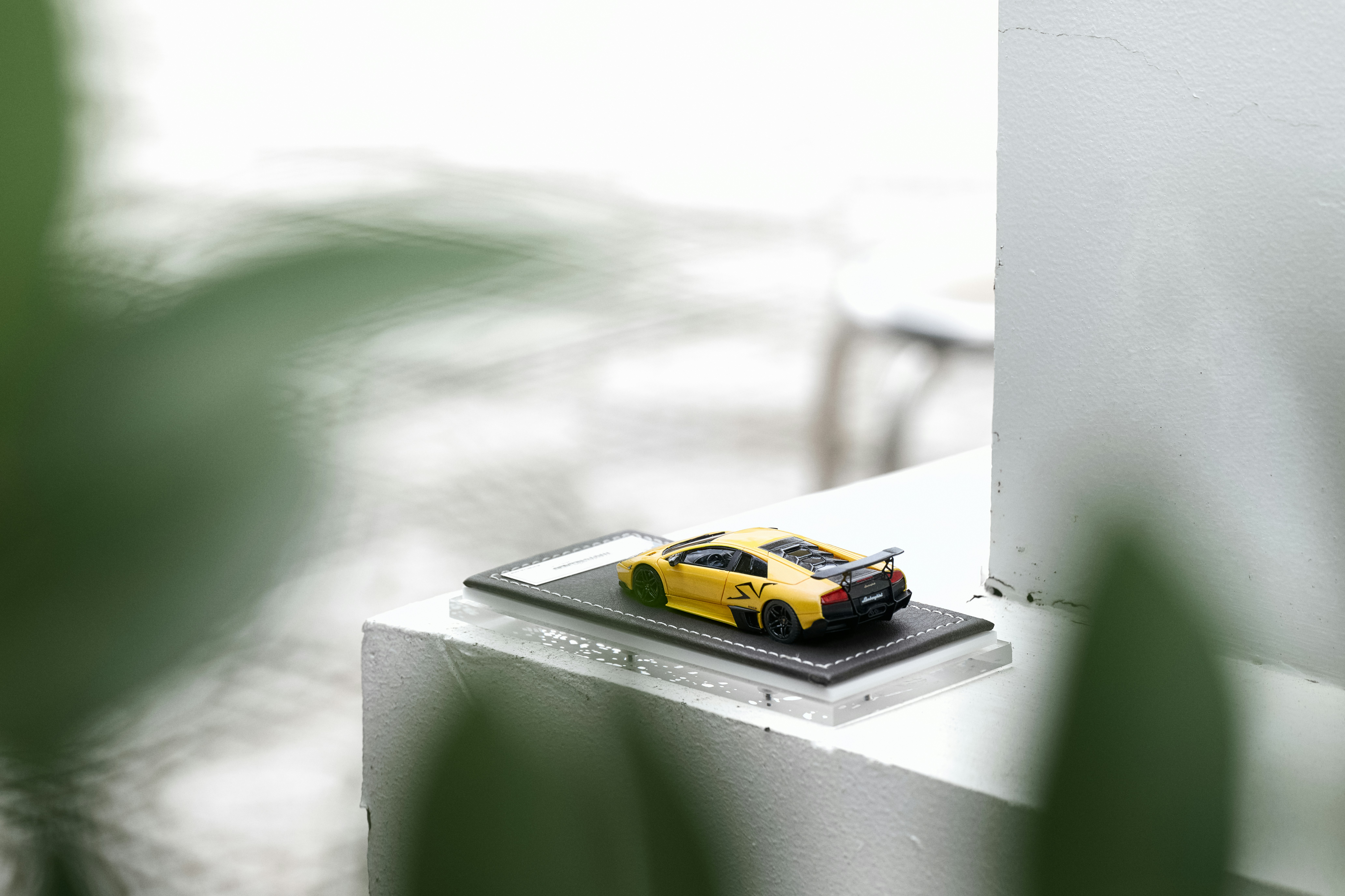 A yellow sports car model on a display base on a white ledge