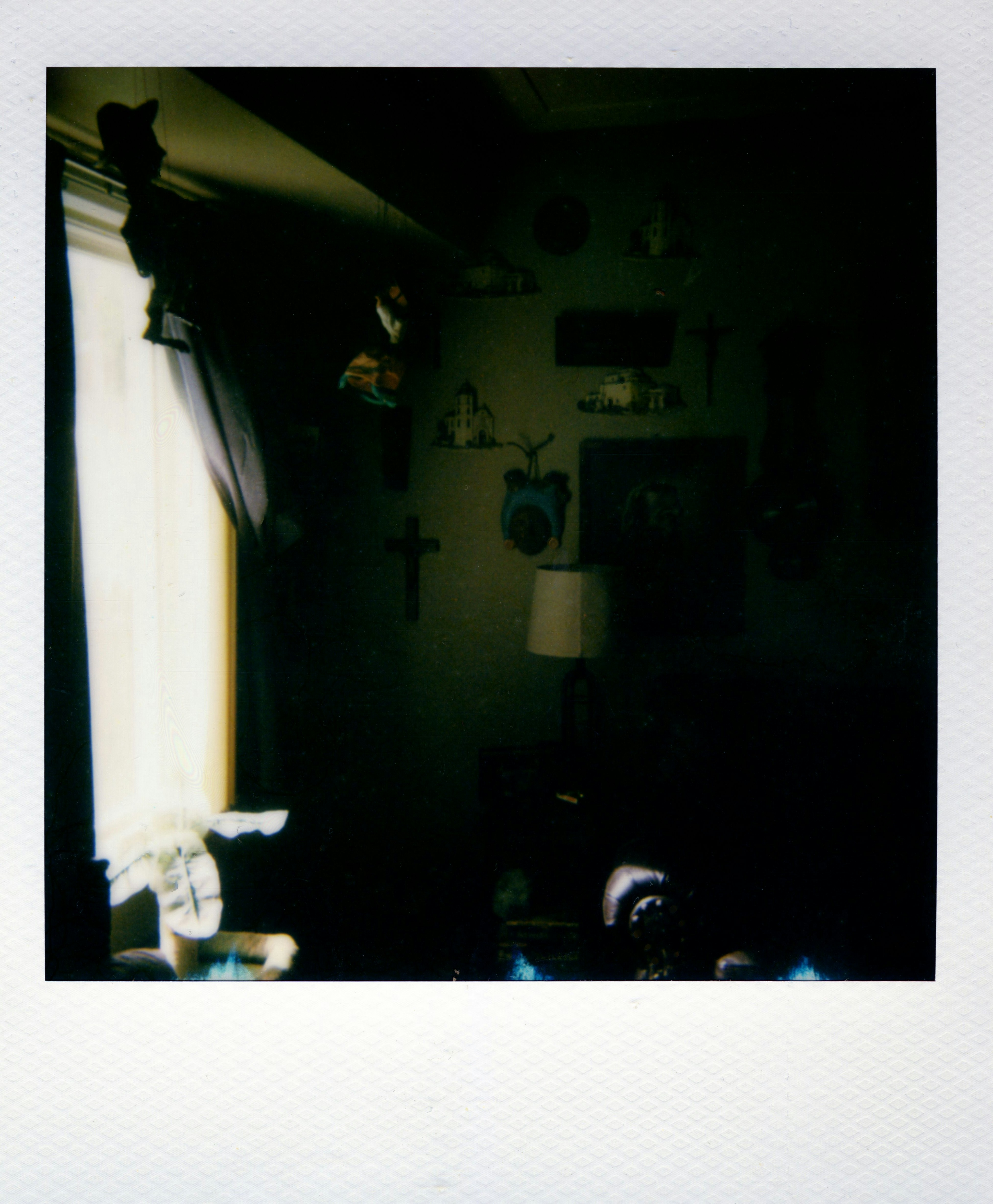 A dimly lit room with wall decorations including crosses and small framed pictures